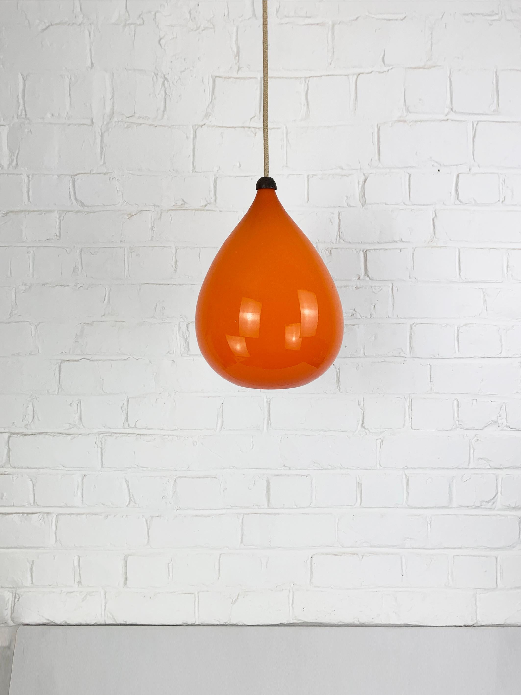 Lampada a sospensione a goccia modernista degli anni '60. 

Vetro arancione con interno in opalina bianca ed elemento superiore in teak. In ottima forma.

Attribuito a Uno & Östen Kristiansson per Luxus Vittsjö, Svezia.

Ottimo stato, nessuna