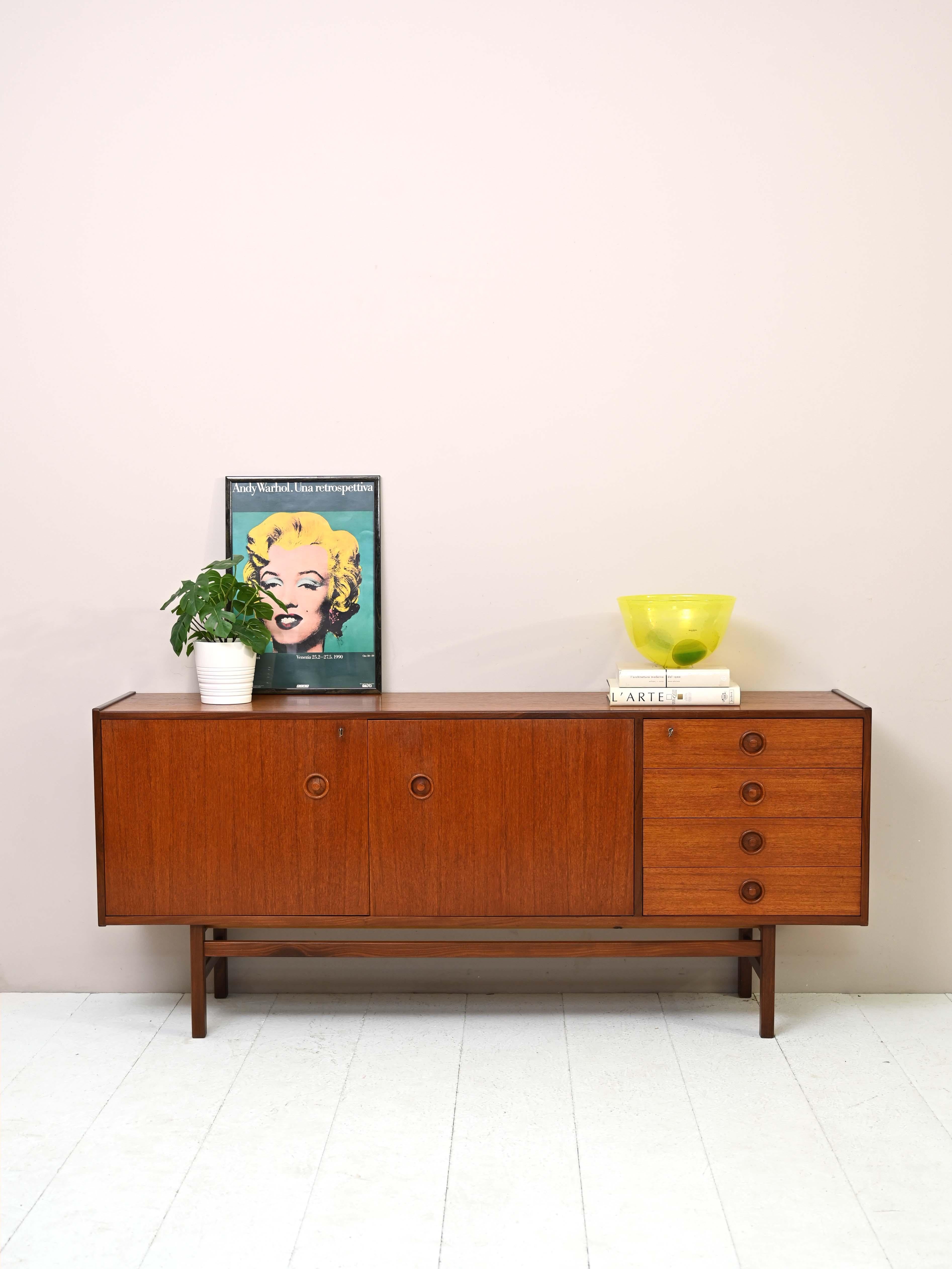 Particular sideboard of Nordic manufacture from the 1960s.

This teak cabinet traces the lines and taste of mid-century design. It consists of a large compartment with hinged doors and four drawers located on one side.
It is distinguished by