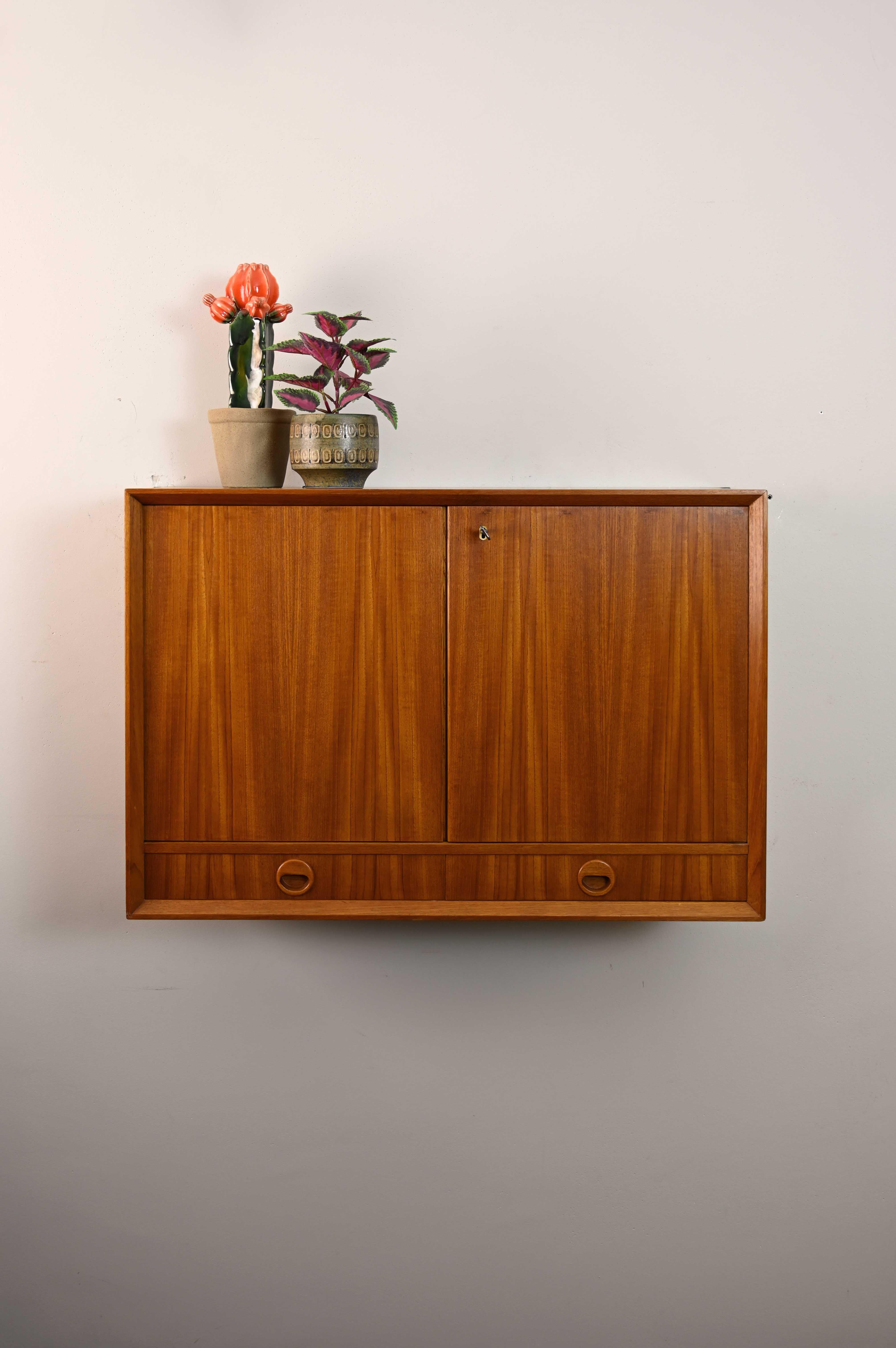 Scandinavian hanging cabinet.

Small storage cabinet, ideal for the bathroom, consisting of a compartment with lockable hinged doors and two drawers.
The teak wood frame with pronounced grains makes it an elegant piece that will characterize the