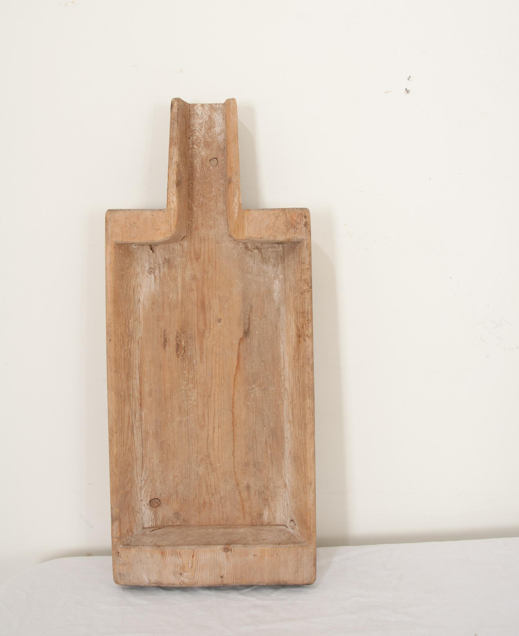 A 19th century Scandinavian cheese maker's board hand-crafted from solid wood circa 1879. Genuine and rustic, this rectangular hollowed out,  paddle shaped board was used for draining and separating the cheese and whey. Made of a solid plank of