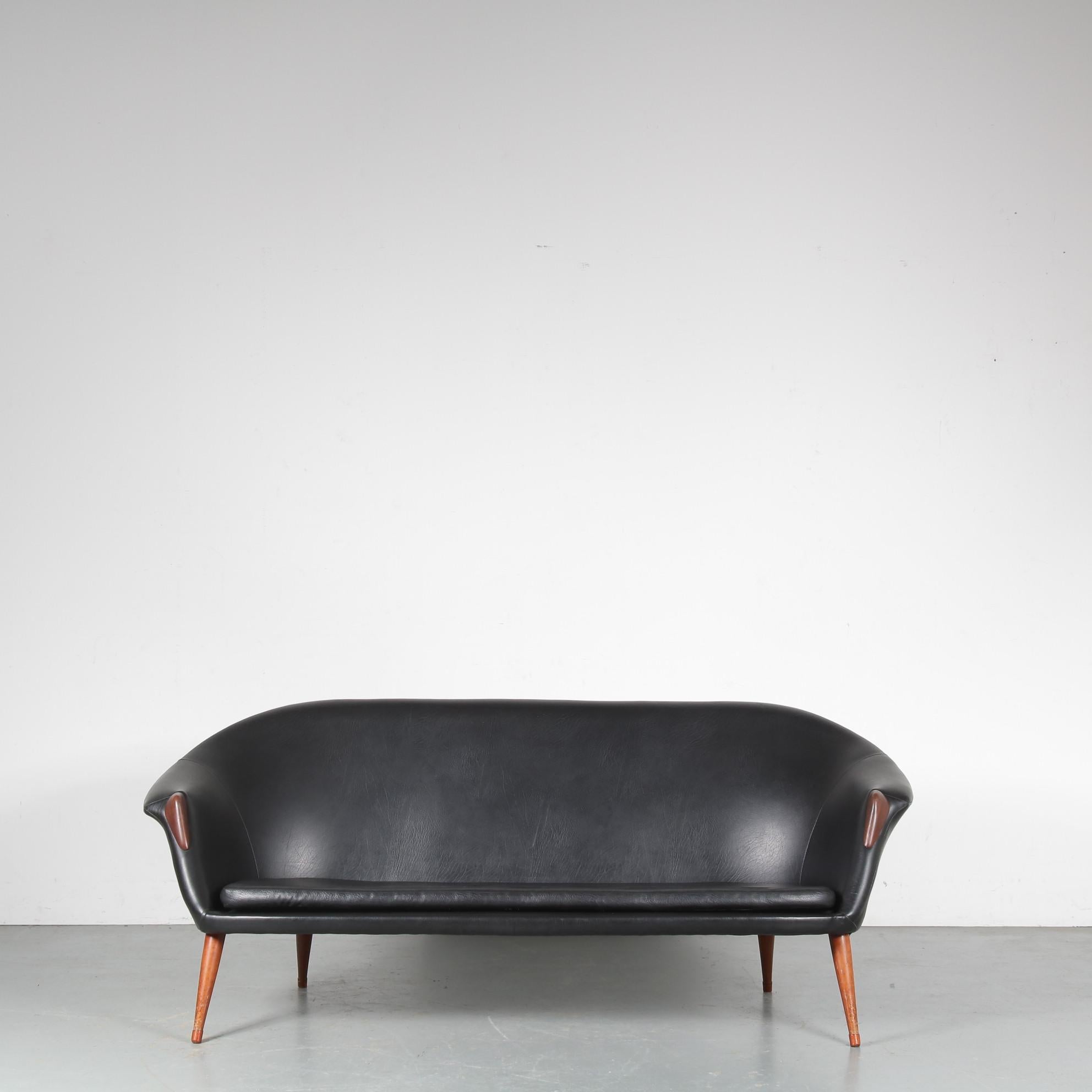 A beautiful 3-seater sofa in Scandinavian style, attributed to Nanna Ditzel, manufactured in Denmark around 1950.

This elegant sofa is beautifully made of high quality black faux leather (skai), nicely complimented by the warm brown wooden legs and