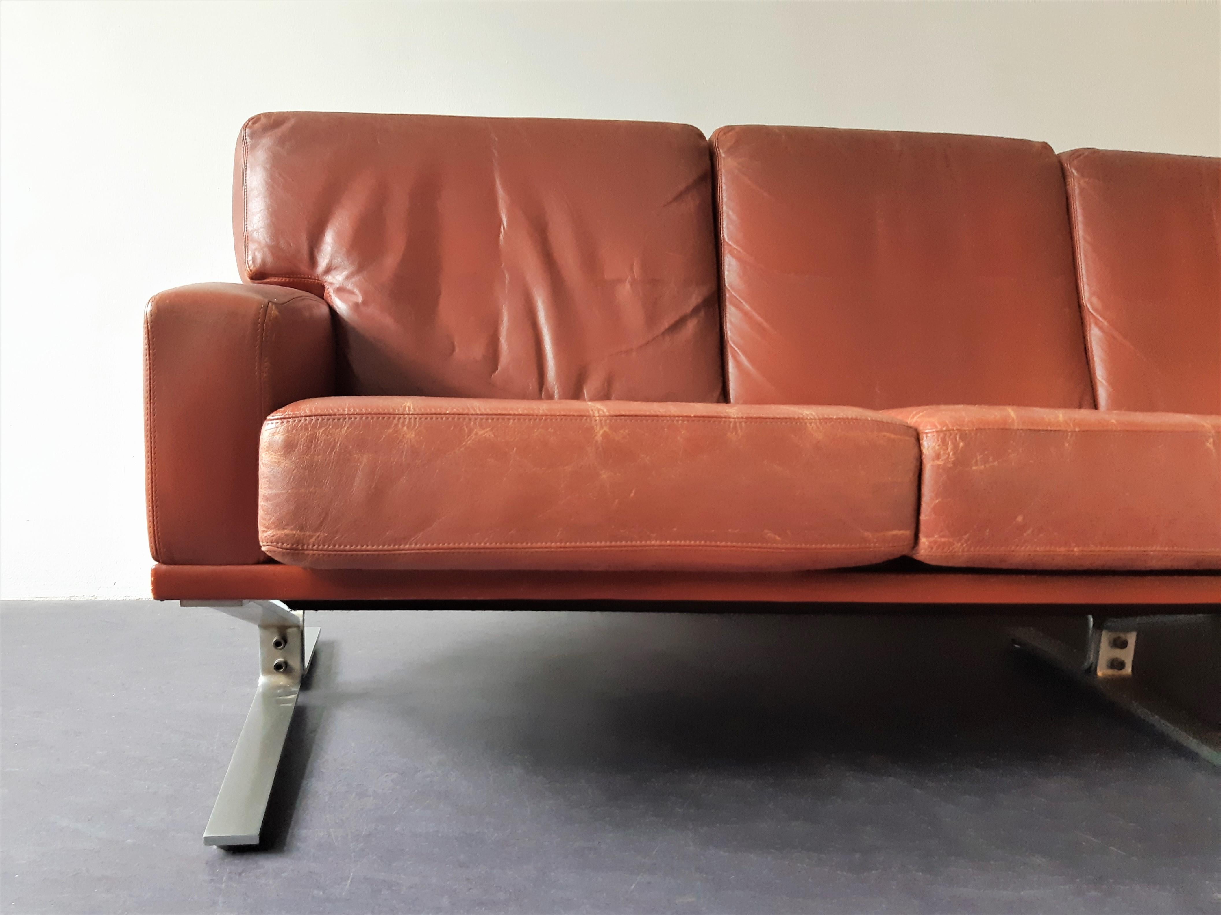 Questo bellissimo divano vintage a 4 posti è spesso attribuito ai designer danesi Georg Thams o Poul Nørreklit. È realizzato in pelle rosso-marrone e ha una struttura in acciaio. Un divano molto confortevole con un'incredibile patina che aggiunge