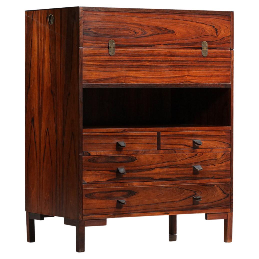 Scandinavian desk or chest of drawers from the 60's, structure in veneered and solid rosewood. This small desk is composed of a folding top with a leather under hand and various clever storage units also in rosewood, as well as four drawers with
