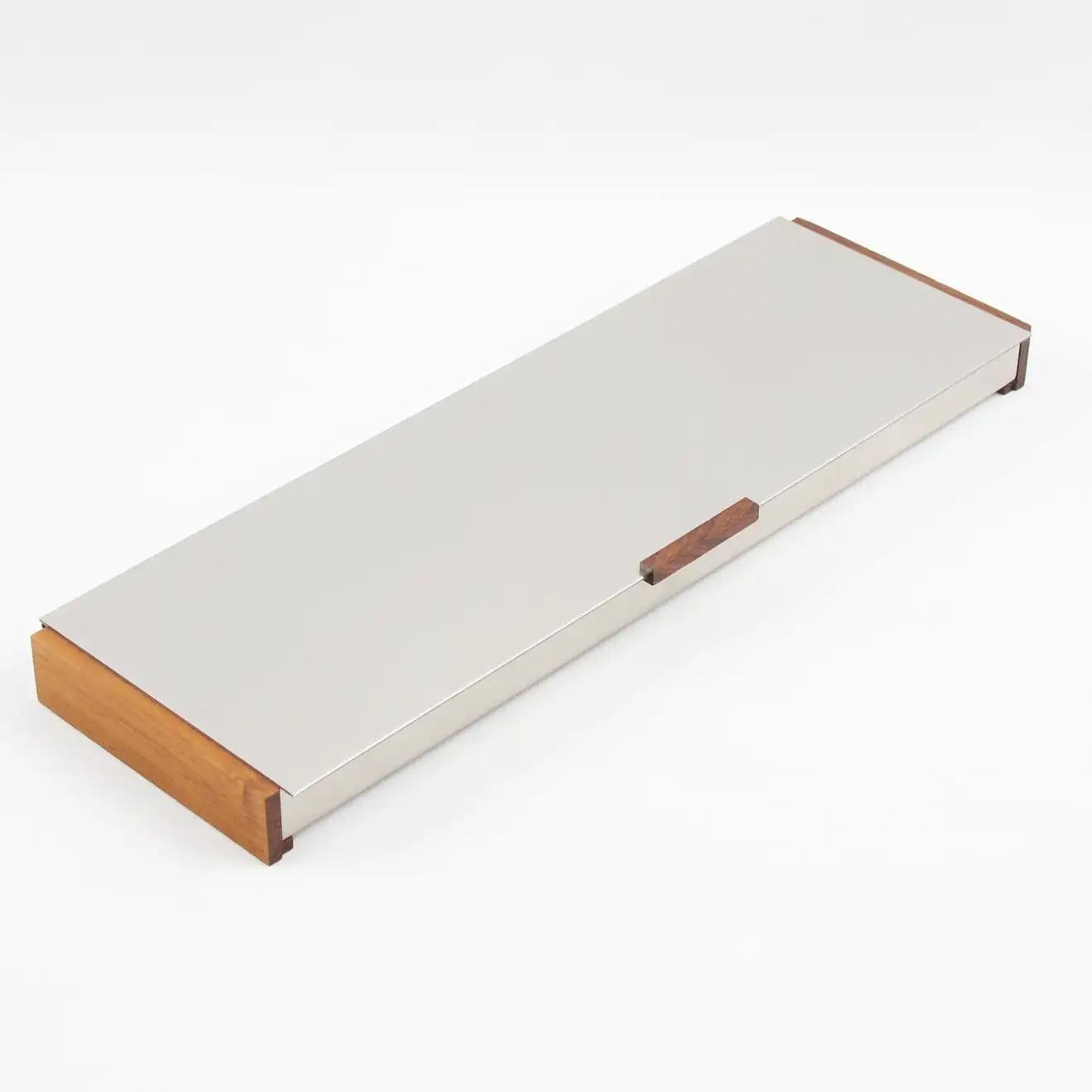 Dansk Form, Copenhagen, crafted this elegant Scandinavian decorative lidded box in the 1970s. The extra-long rectangular and flat shape has a typical Danish design with brushed aluminum and teak wood sides and a tiny handle in teak. The piece is