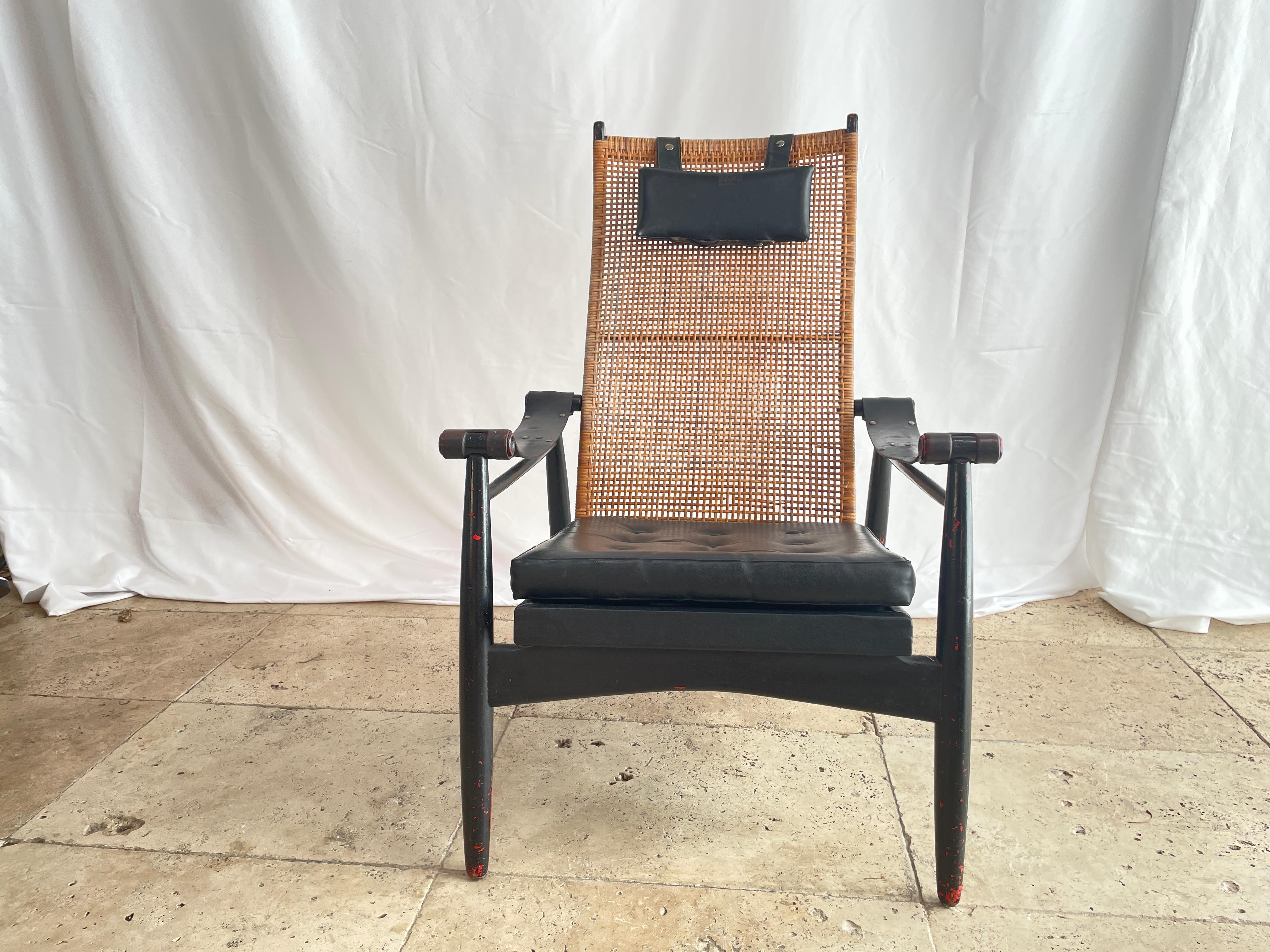 Armchair with low seat in black lacquered wood, cane back, leather armrests,
 Scandinavian work 2nd half 20th century 
wear marks are present on the wood.
the seat straps have been redone, and the seat buttons have been replaced by new ones 
the
