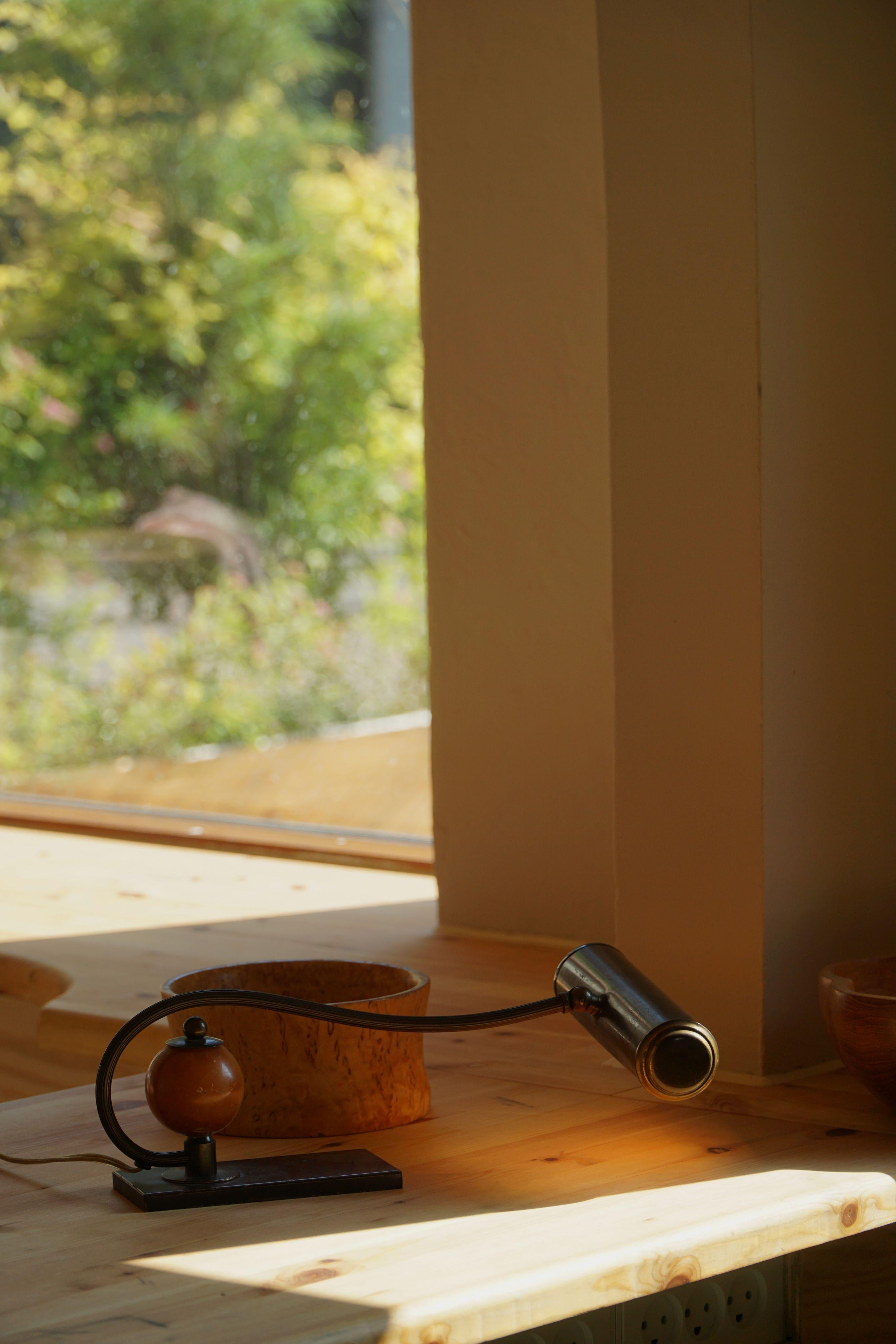 A refined Danish Art Deco piano or desk lamp from the 1930s, combining sculptural elegance with functional charm. The lamp features a slender, curved brass arm supporting a cylindrical brass shade, offering focused and atmospheric light—ideal for