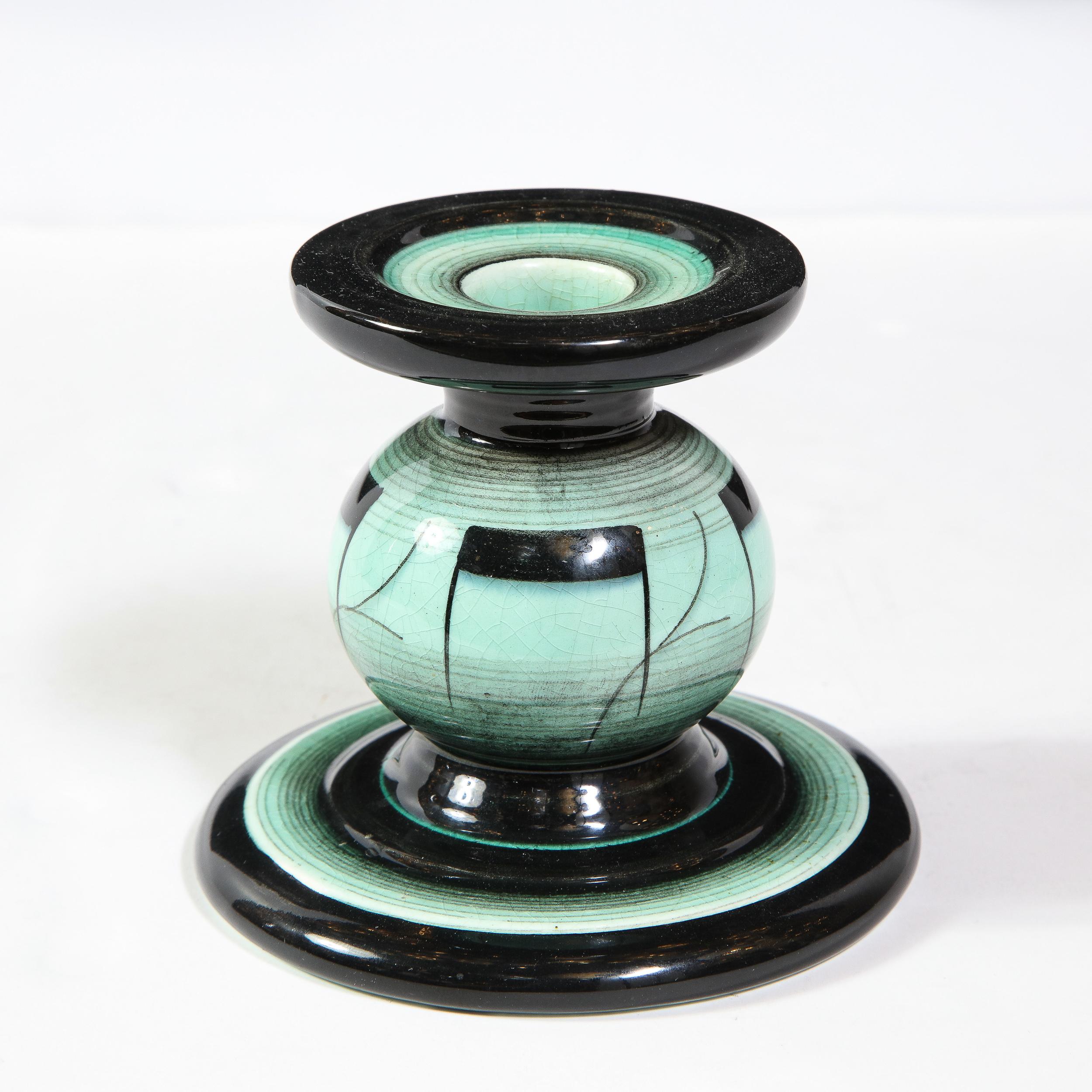 This refined Art Deco glazed ceramic candle was designed by Ilse Claesson for Rörstrand in Sweden, circa 1930. It features a stylized hour glass form with a striated onyx glazed base and a sea foam center with abstract hand painted motifs, as well