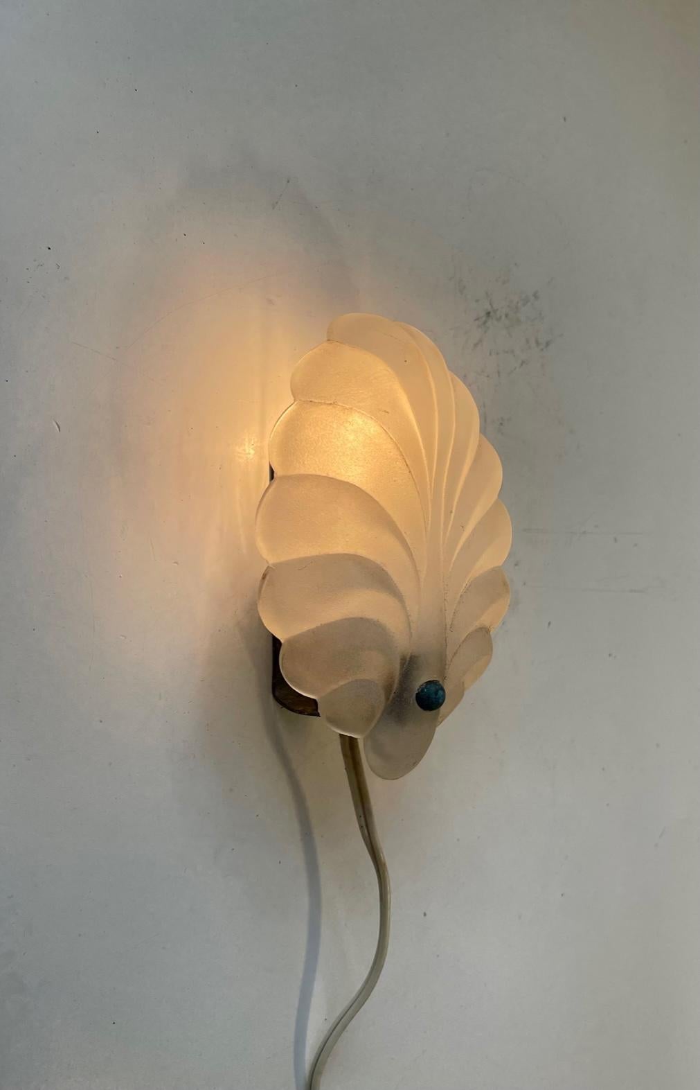 Small decorative wall light in frosted glass in the shape of a shell. Held in place to the mount by a patinated brass ball. It was Manufactured in Scandinavia in the 1930s in a style reminiscent of C. T. Kalmar and Orrefors. Measurements: H: 15 cm,