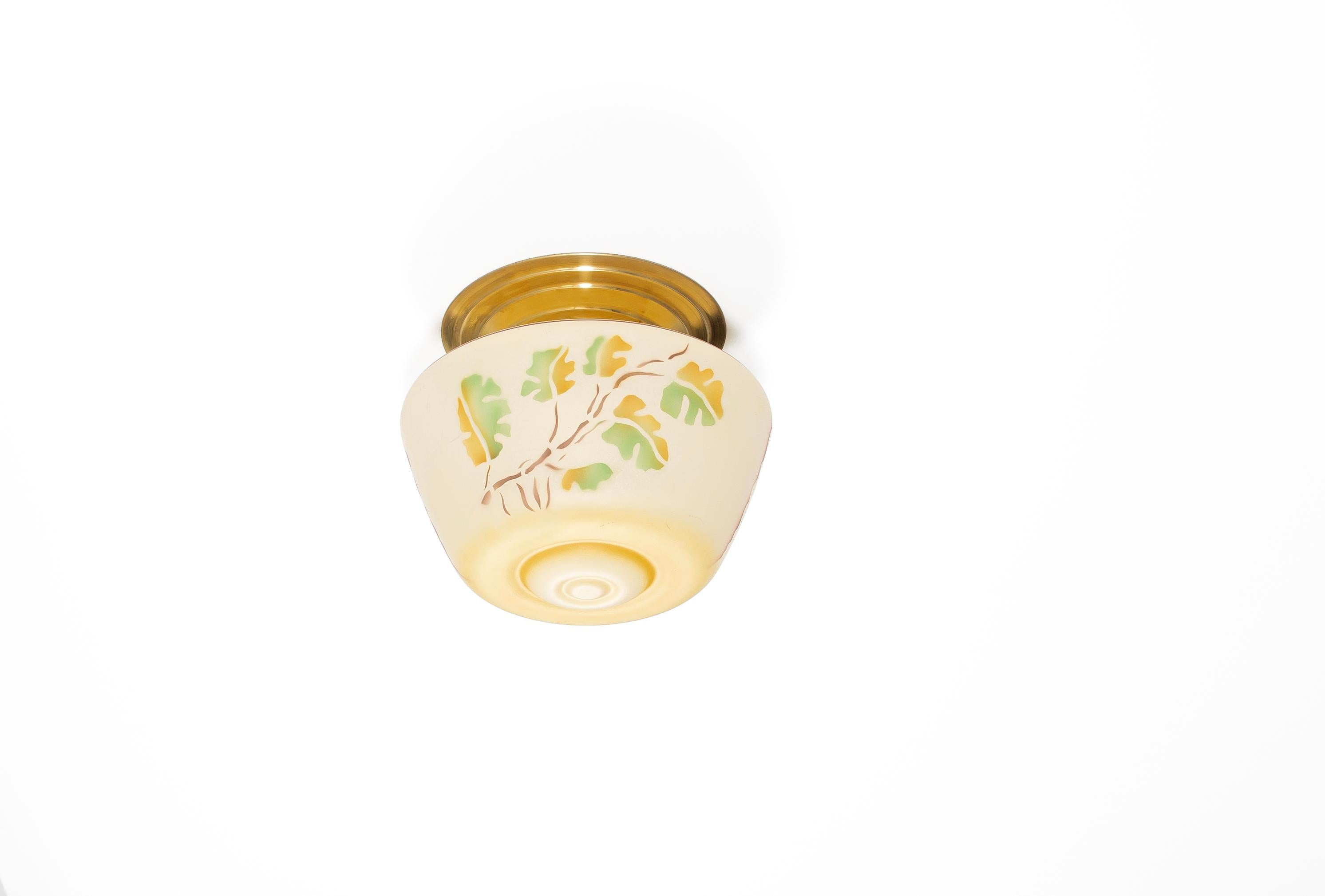 Wonderful, decorative, and very rare art deco ceiling light with hand-decorated glass shade and brass metal base. Designed and made in Norway from ca 1920s first half. The lamp is fully working and in very good vintage condition. It is fitted with