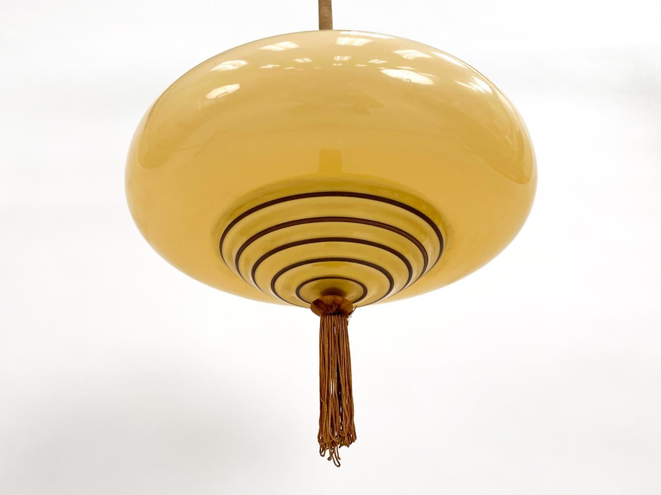 This captivating Art Deco glass ceiling light is a radiant gem hailing from Scandinavia, circa 1930s. This pendant fixture embodies the sophisticated glamour and geometric artistry of the Art Deco era, infused with a touch of Scandinavian design