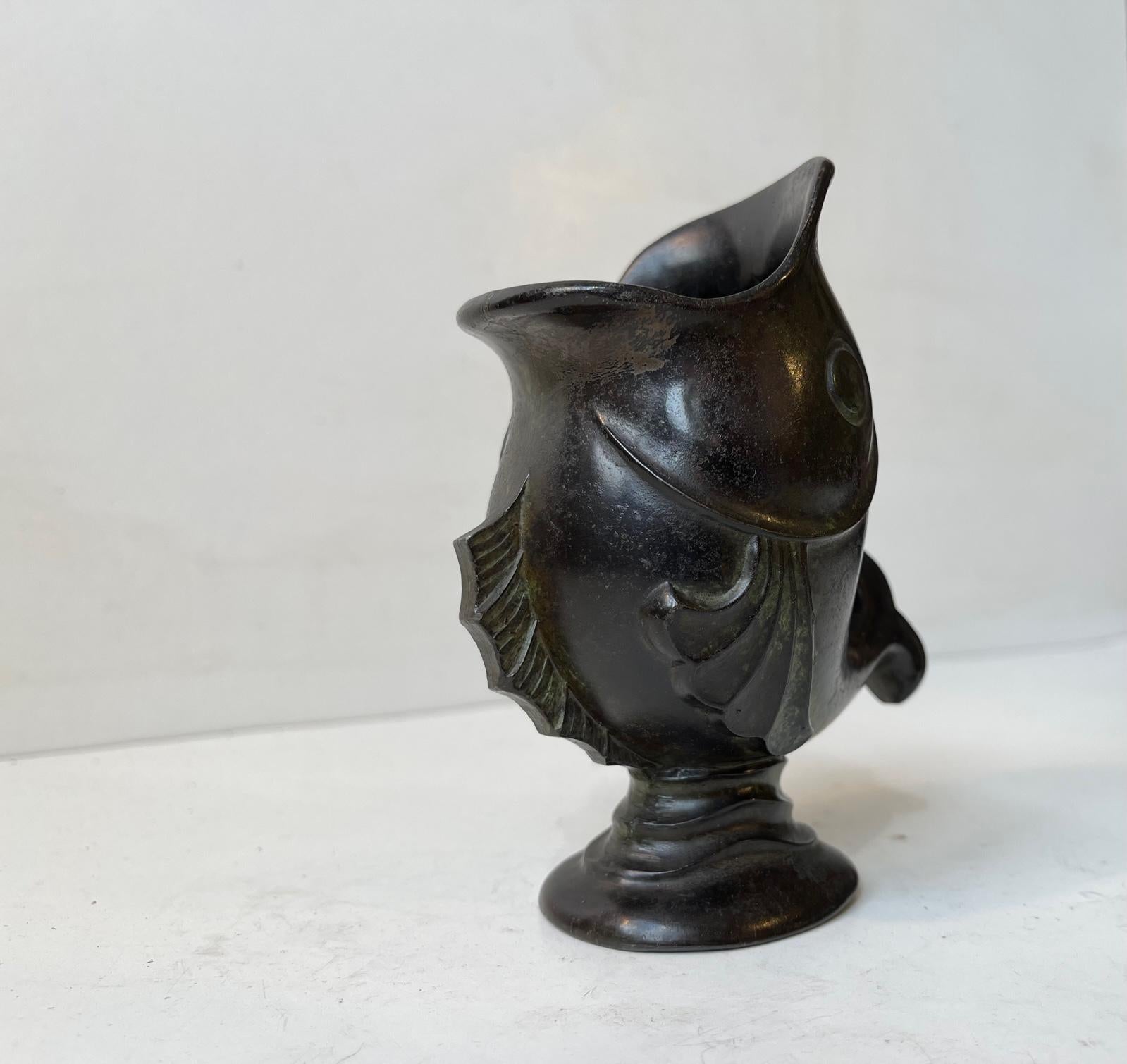 A small figural vase depicting a rising koi fish. It made from patinated metal/metals and is of Scandinavian origin. Possibly a slip-up from Just Andersen since it has no markings but is very much in his style. Measurements: H: 13 cm, W: 11 cm,