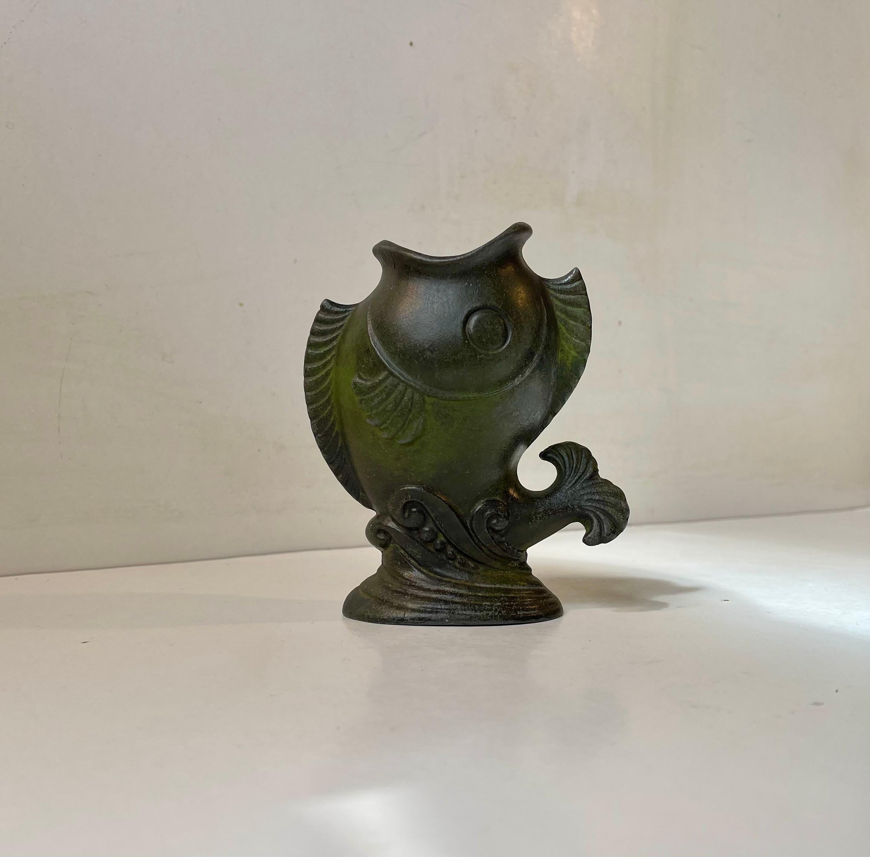 Un piccolo vaso figurato che raffigura un pesce koi in risalita. È realizzato in metallo/metalli patinati ed è di origine scandinava. Probabilmente si tratta di un errore dell'officina Just Andersen, dato che non presenta alcuna marcatura ma è molto