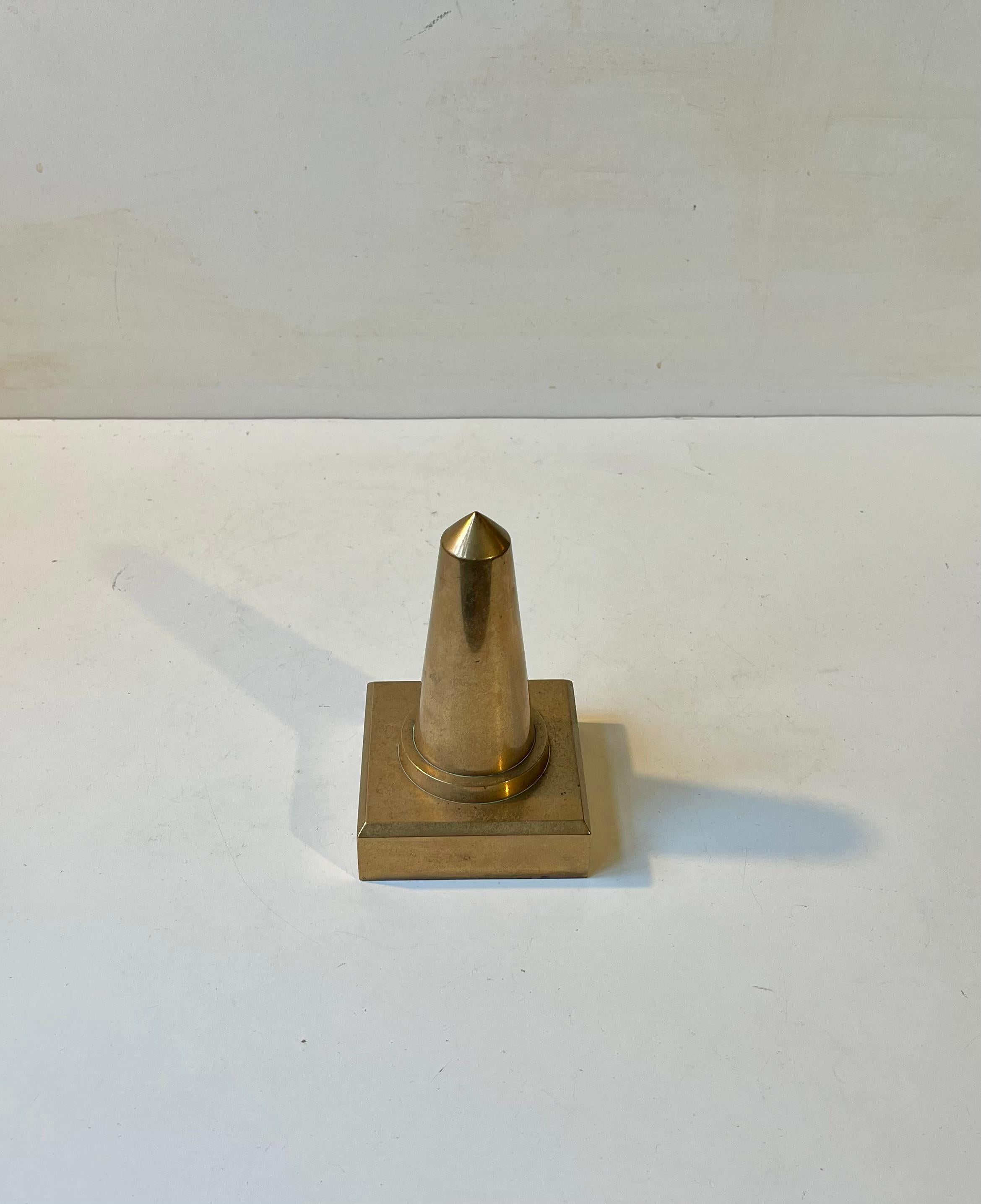 Elegant and simplistically constructed desk ornament or paperweight in bronze. The obelisk can be perceived as a phallic symbol, a creating force or even a symbol of the sun. Its clean diminutive shape has been implemented in both ancient and modern