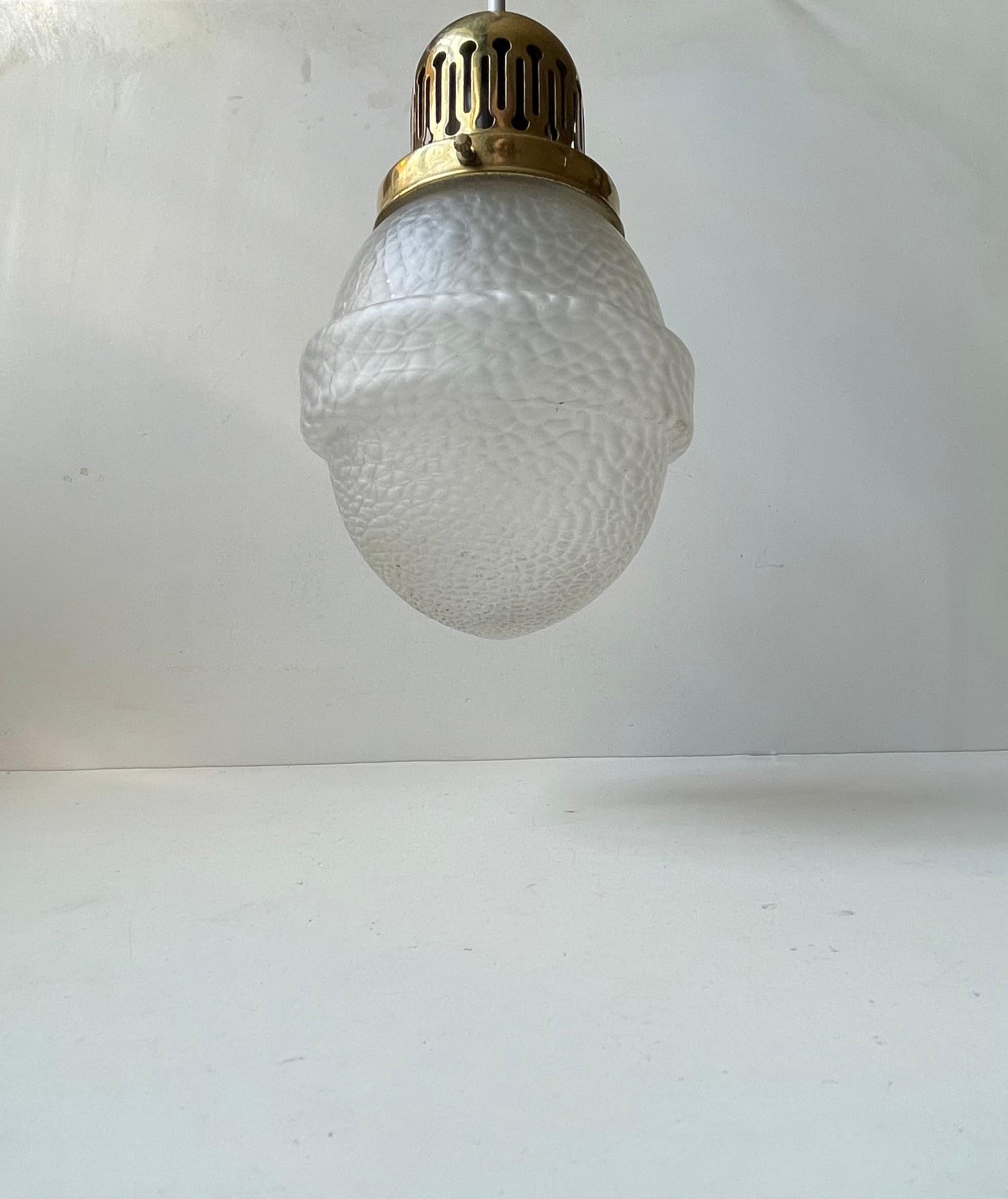 A 1930s ceiling light composed of a partially perforated brass top and a frosted glass shade with lizard skin pattern. It was made an unknown maker in Scandinavia during the 1930s. 

It comes tested and with 2.5 meters new white cord. 