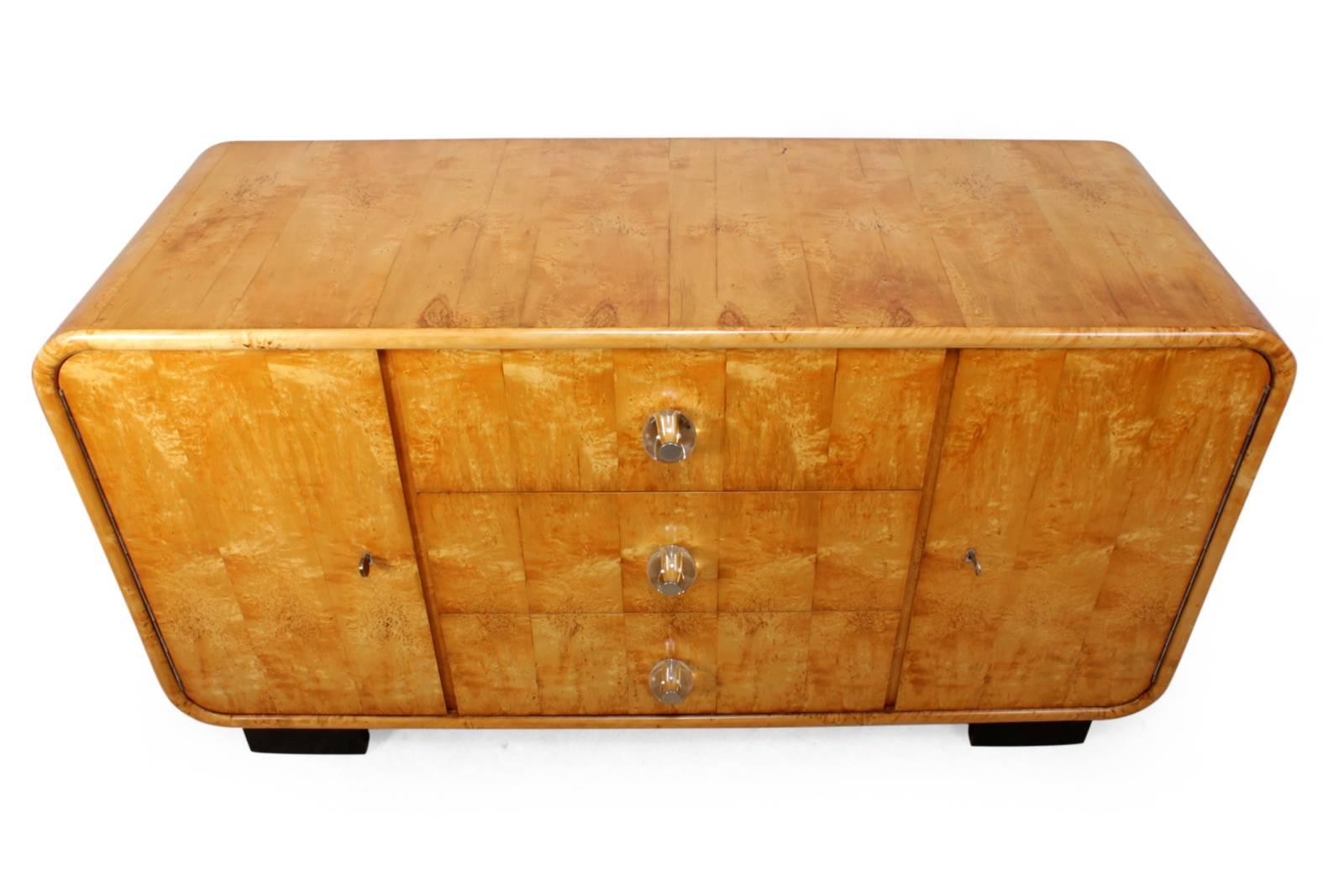 Scandinavian Art Deco sideboard
This art deco revival sideboard produced in the 1950s veneered in karelian birch it has two doors with adjustable shelved behind, it has three central drawers with glass handles.

Age: 1950

Style: Art