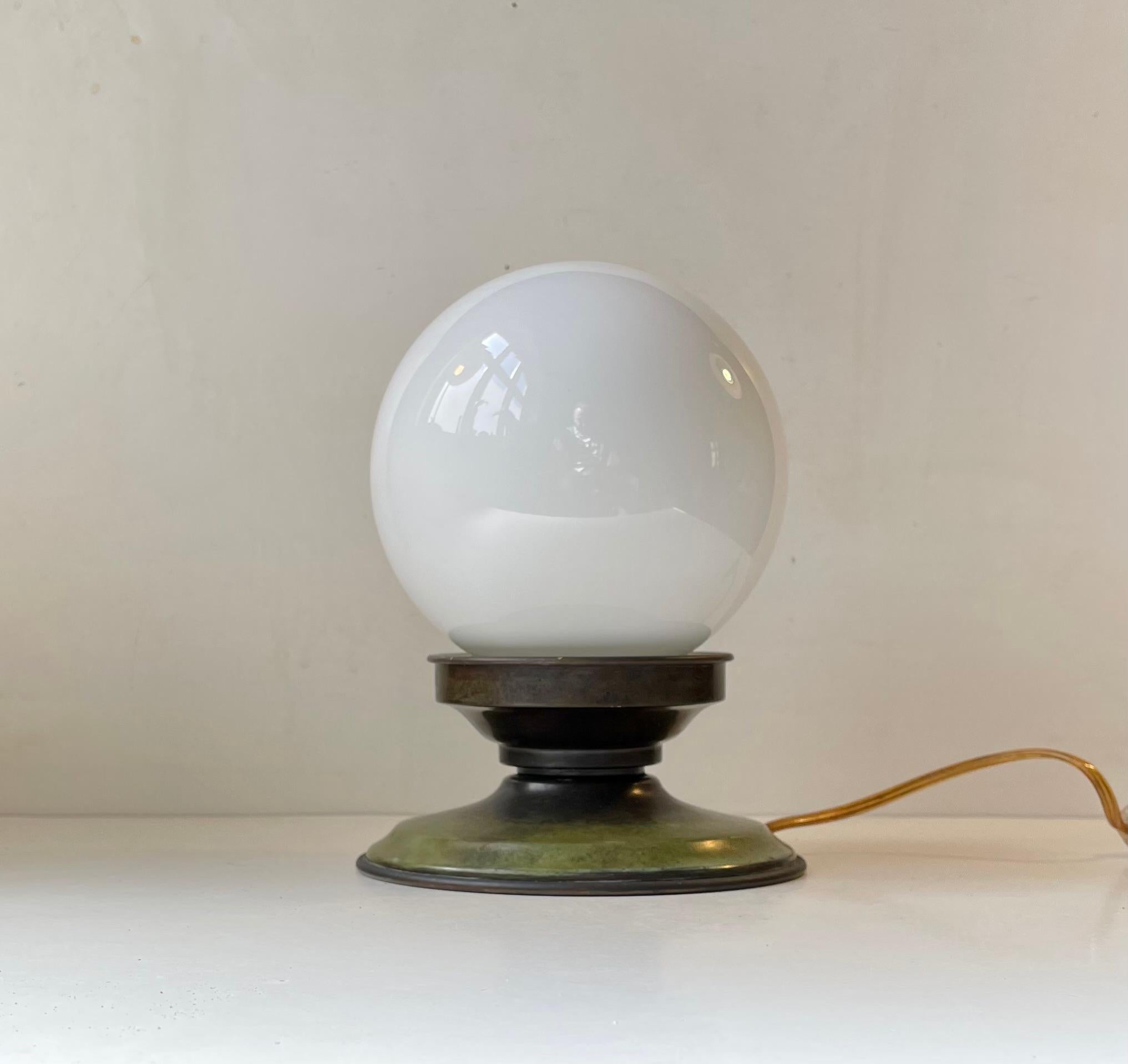 A well made possibly up-cycled table lamp made from green verdigris bronze and installed with a spherical white opaline glass shade. This small table light features a 1930s socket in brass and porcelain. A more recent wire with on/of switch has been