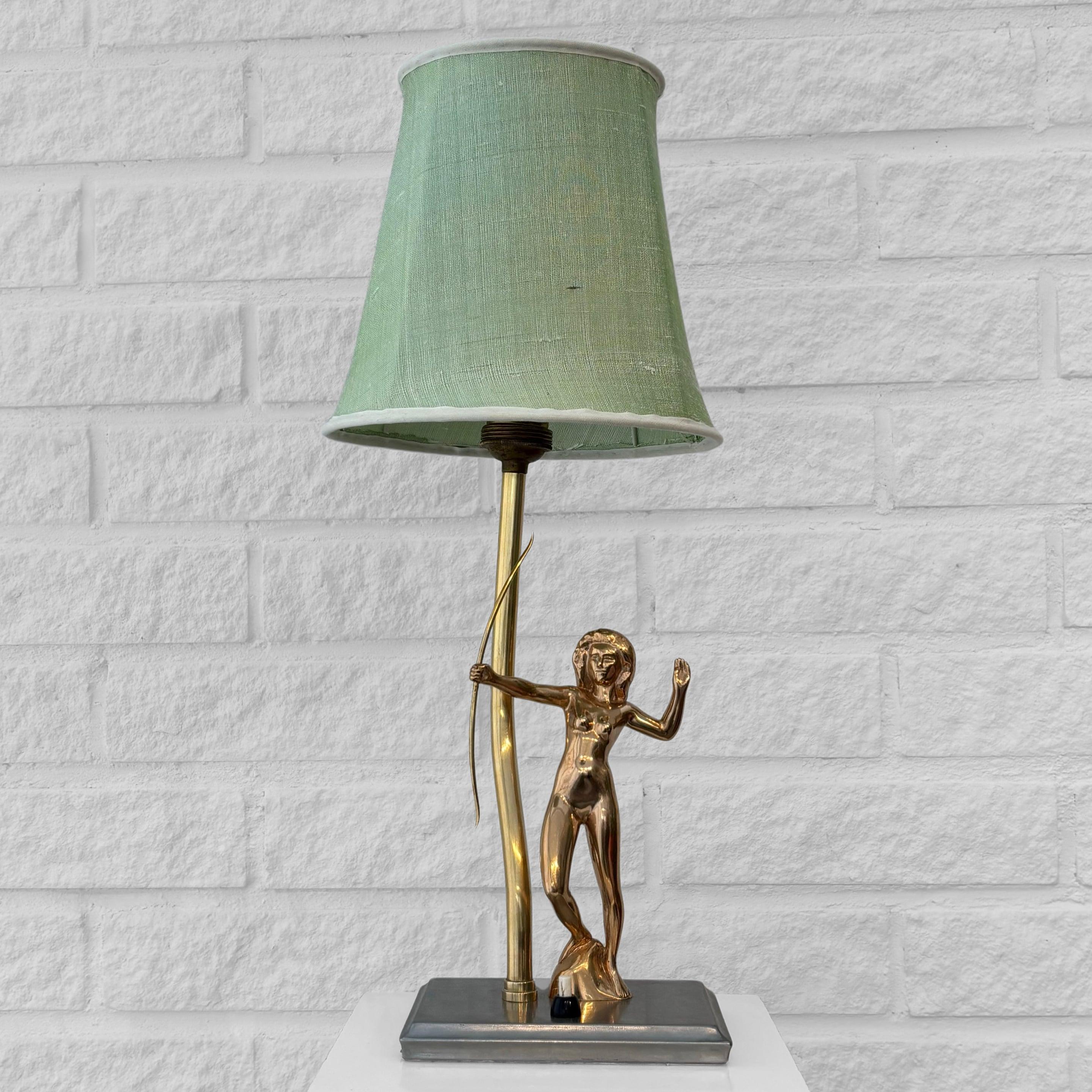 This exquisite Art Deco table lamp, attributed to the Swedish manufacturer Stjärnmetall, captures the elegance of 1920s design. The lamp features a striking nude female archer sculpted in solid brass, poised on a rectangular cast iron base with an