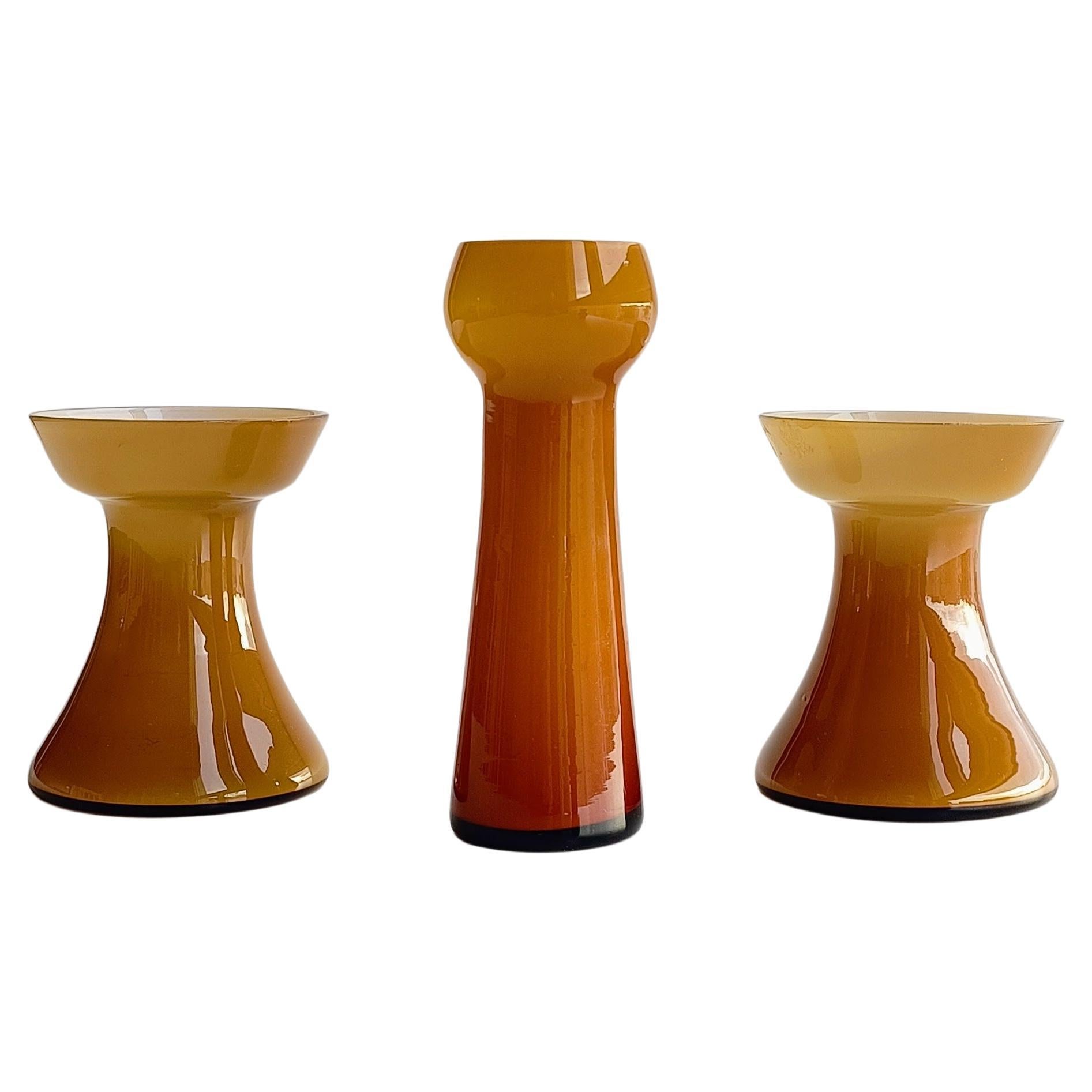 A set of three beautiful Scandinavian Modern amber cased glass candle holders by Per-Olof Ström for Alsterfors Glass. Handblown in Sweden, circa the 1950s.

Per-Olof Ström was a Swedish glass designer known for his work during the mid-20th century.