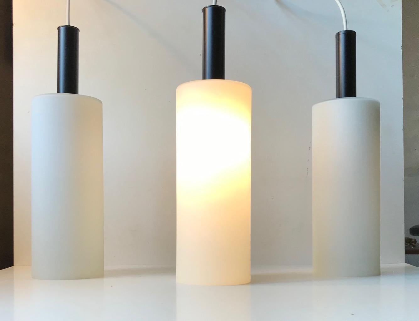 A trio of 'hammer' or 'mallet' shaped pendant lamps composed of matté cased opaline glass and top made from powder coated steel. Designed and manufactured by Lyfa in Denmark during the 1970s in a style reminiscent of Stilnovo.
