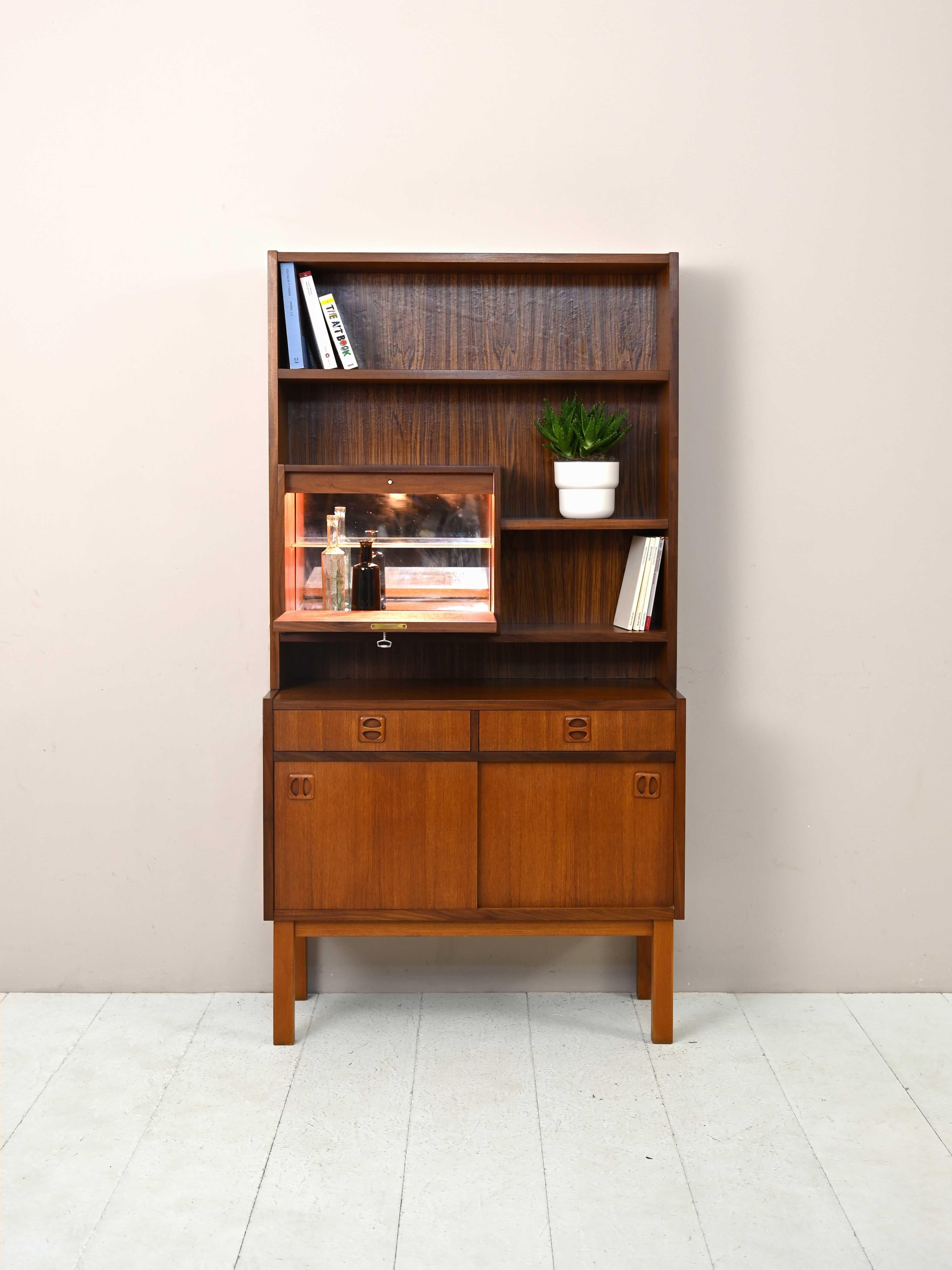 Scandinavian cabinet with shelving and bottle compartment.

A practical and original bookcase consisting of a cabinet with sliding doors and two drawers and a shelving system with adjustable height. There is a mirrored bar compartment equipped
