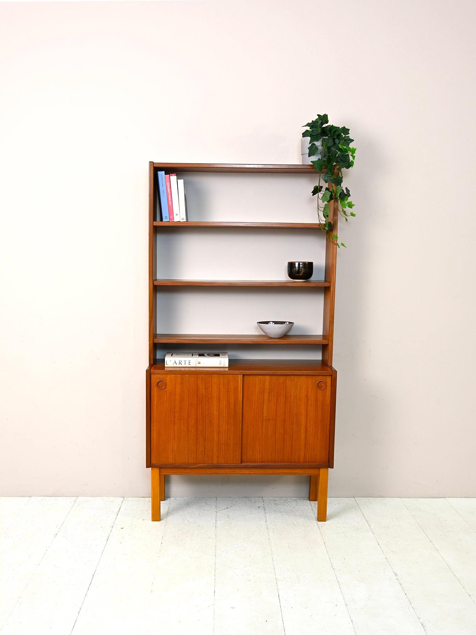 Scandinavian vintage cabinet with shelving.

A functional modernist piece of furniture with simple, minimal lines.
Consists of a small sideboard with sliding doors on which rests a shelving system with adjustable height.
A bookcase with small