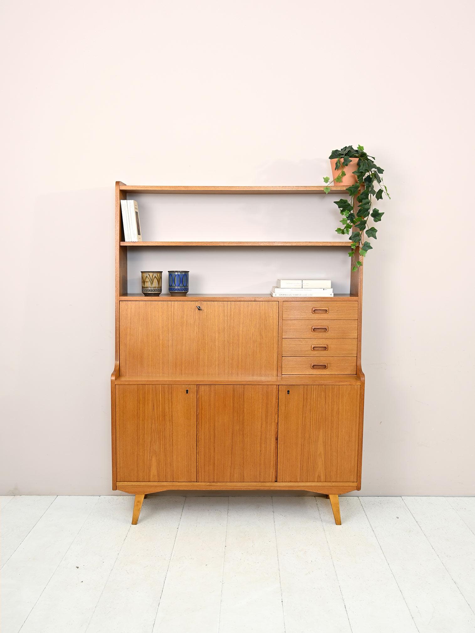 Original teak cabinet from the 1960s.

In the upper part there is shelving and a drop-down top that converts to a convenient writing desk when needed.
In the lower part the three hinged doors enclose a storage compartment equipped with a shelf on