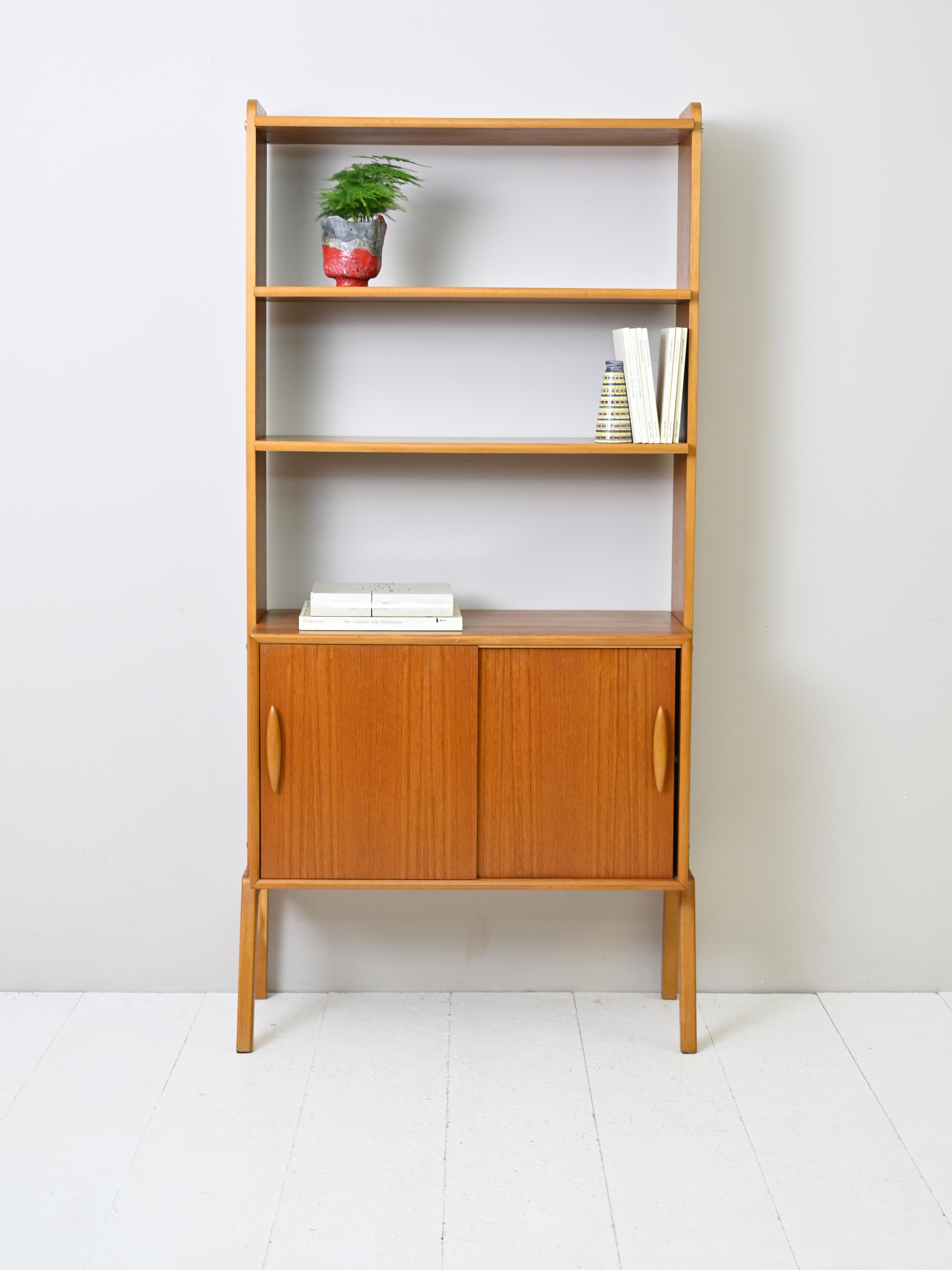 Vintage Swedish cabinet with classic mid-century lines.

The lower part is a small sideboard with storage space and sliding doors while the upper part is a bookcase with two adjustable-height shelves.

The carved wooden door handles and minimal
