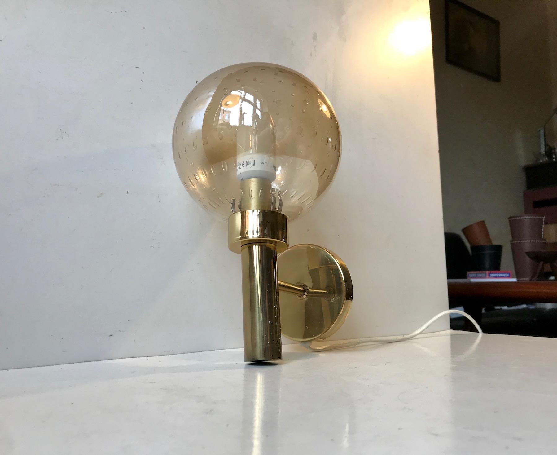 Lounge sconce with spherical honey colored glass shade with controlled bubbles. It was manufactured and designed by Vitrika in Denmark in a style reminiscent of Hans-Agne Jakobsson. Nice vintage and working order with a light patina to the brass