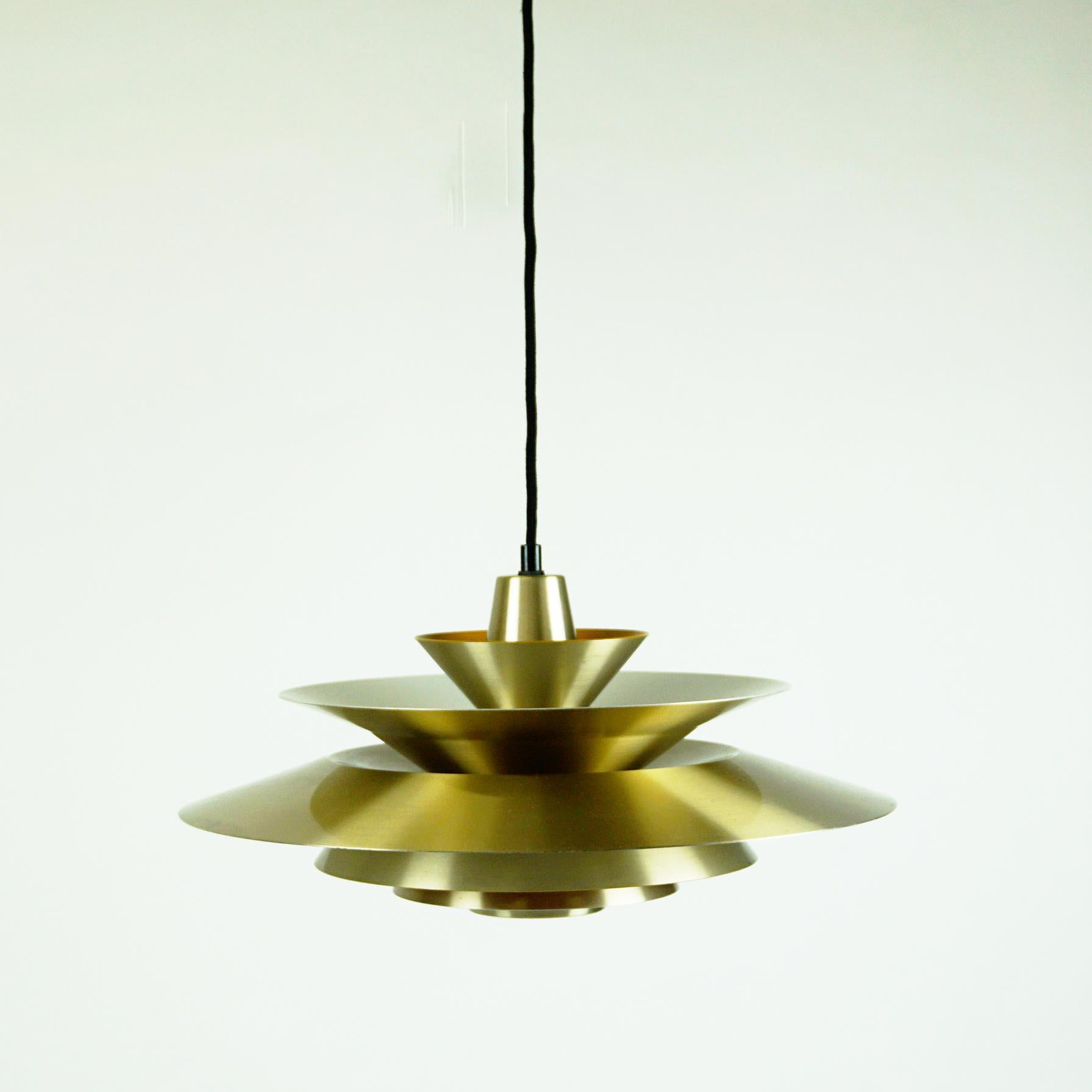 This charming brass pendant was designed in the 1960s in Denmark and its design is very close to lamps by Jo Hammerborg, main designer of Danish lighting manufacturer Fog & Mørup in the 1960s and 1970s. On the Inside it is lacquered yellow to create