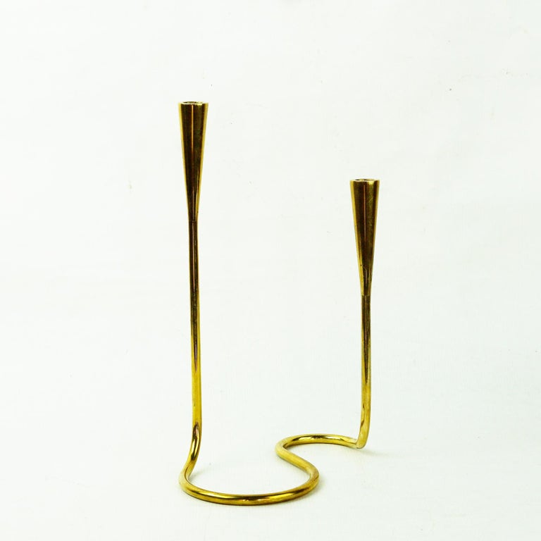 This elegant and curvaceous brass candlestick was manufactured and retailed by Illums Bolighus in Denmark. Concerning the Designer others often attribute it to Carl Aubock, but with no conclusive proof that these are his. 
However, there are