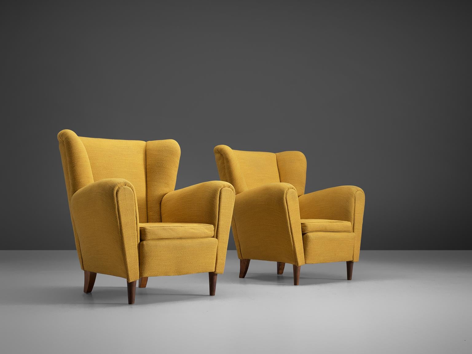 Set of armchairs, fabric, wood, Scandinavia, 1950s.

This set of lounge chairs is both voluptuous and grand as they are comfortable. The chairs have semi high wingbacks and feature yellow piping and small tapered wooden legs. Typical curvy, bold
