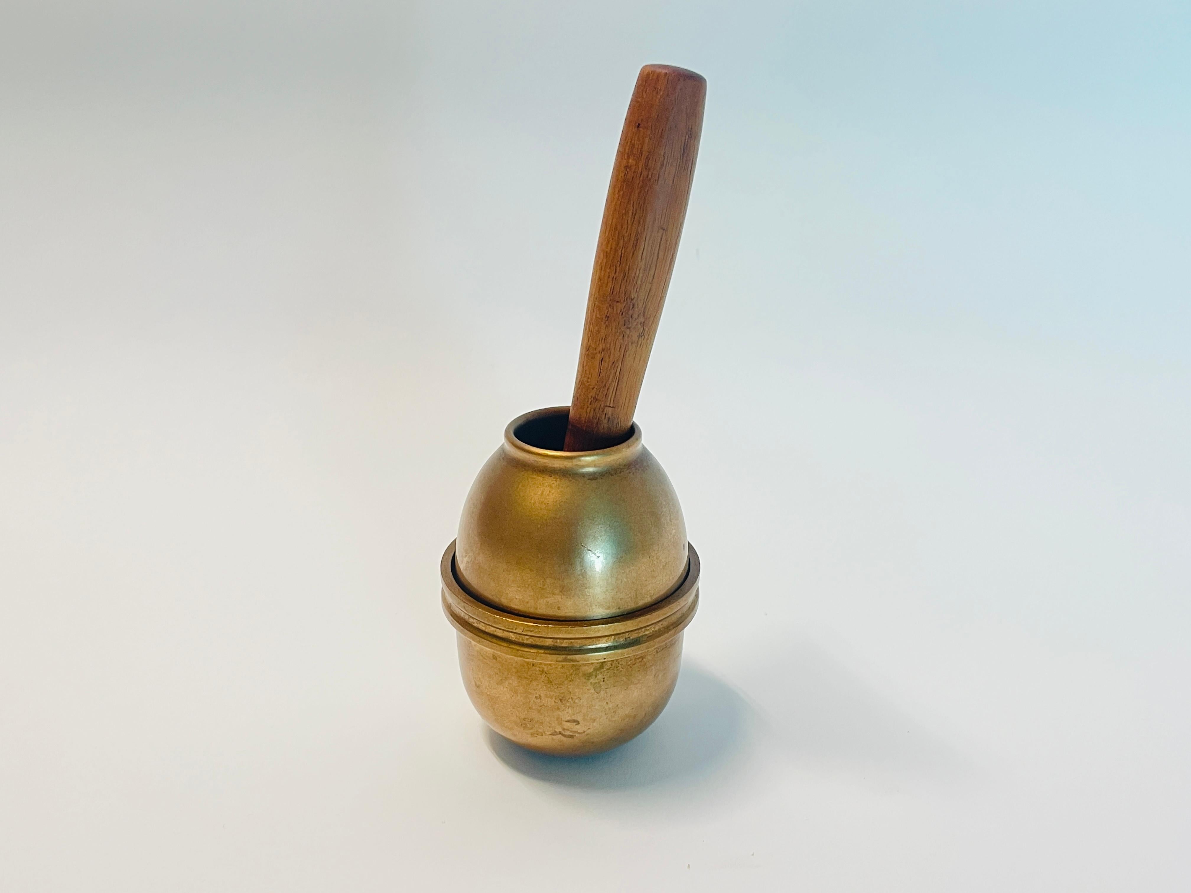 Impresionante y escultural mortero diseñado por Bertel Gardberg para BODA en la década de 1950. 

La cubeta del mortero está hecha de dos piezas de bronce macizo y el mortero es de madera de teca y bronce. El mortero se abre por el centro para