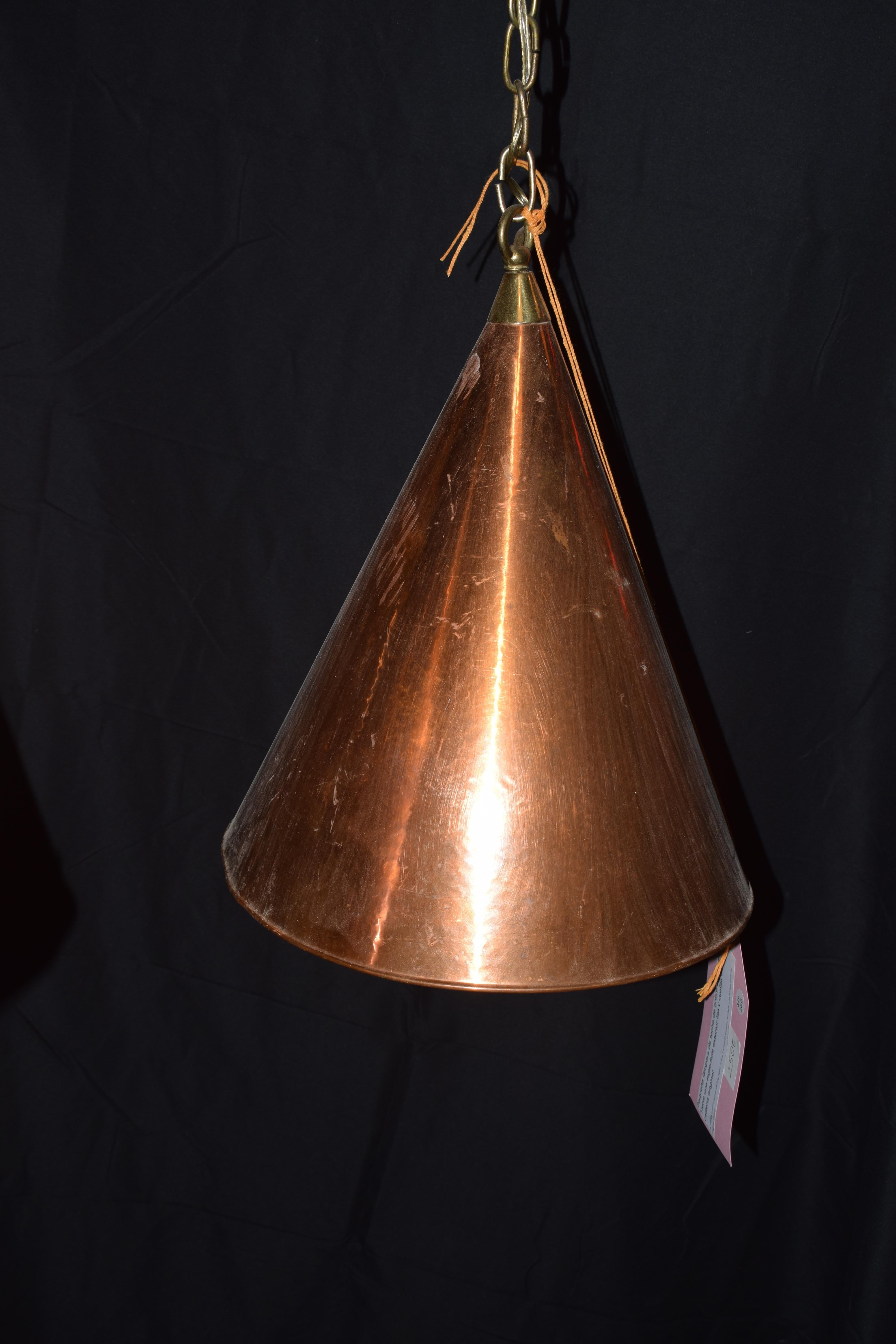 A Scandinavian Brutalist Danish copper pendant lamp. It is handcrafted and has its original hanging chain. It is elegantly hand hammered copper cone pendant lamp hanging on long chains.The shape is conical and its style is in a minimal style. It has