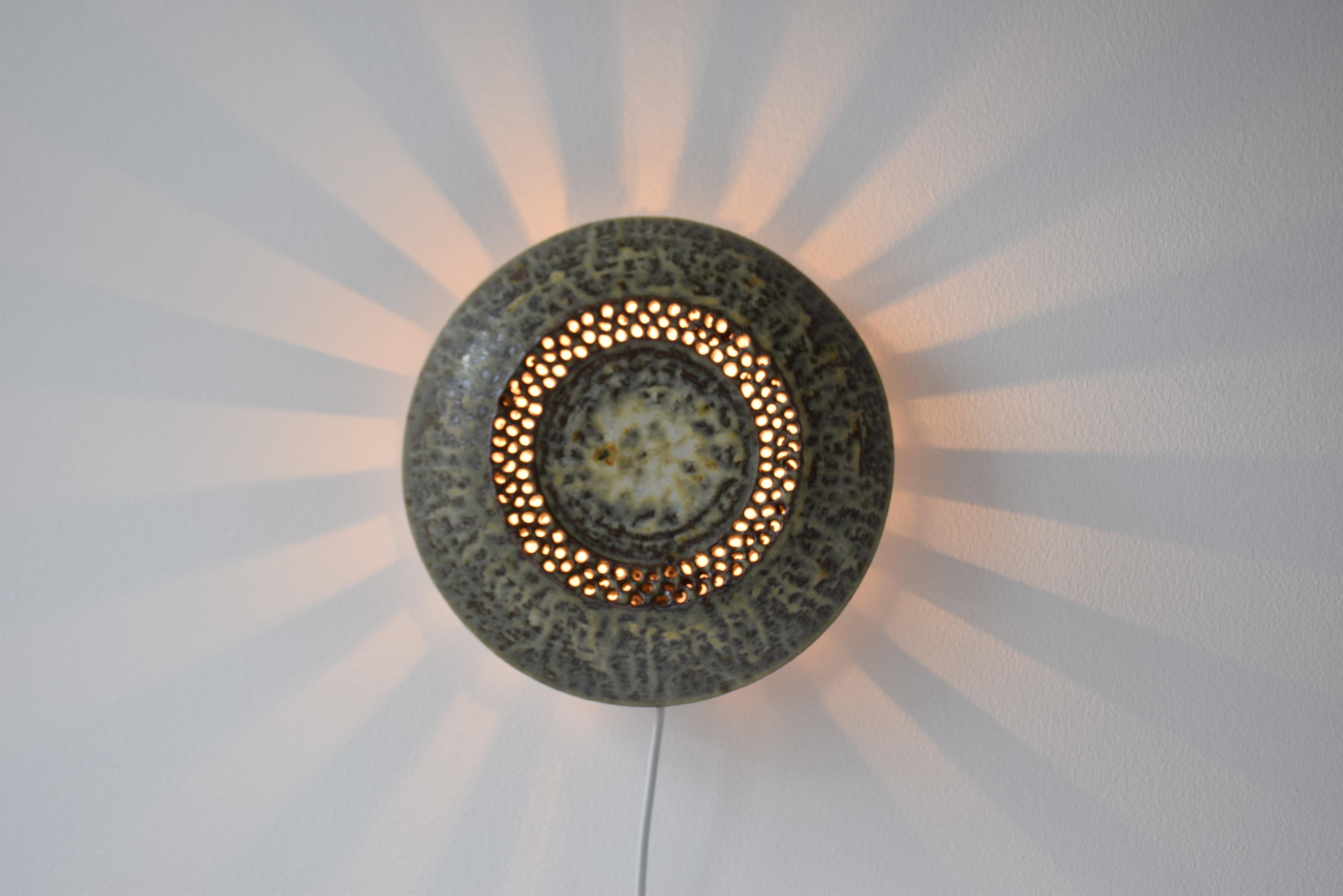 Decorative sun shaped ceramic wall sconce, most likely from a Danish or Scandinavian ceramic workshop. It's in the style of wall sconces by Sejer Keramik, Kingo Keramik and Søholm Keramik.

The vertical openings at the side casts light like
