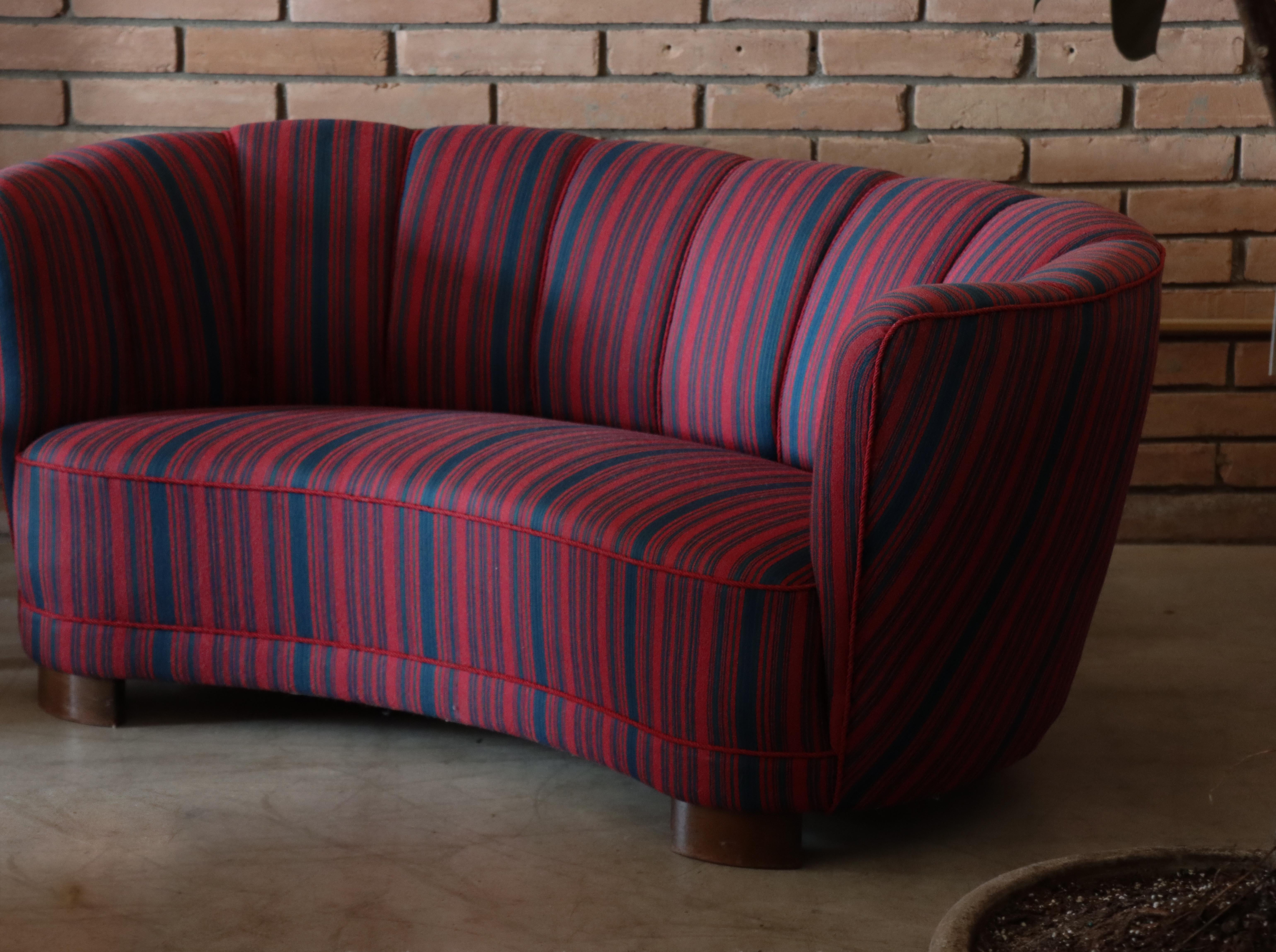 Este sofá de ebanista encarna la elegancia del diseño del siglo XX. Su escultural forma de plátano se curva con forma acogedora, mientras que el original tejido a rayas aporta un ritmo de rojo y azul marino intenso. 

Apoyada sobre patas de pala, la