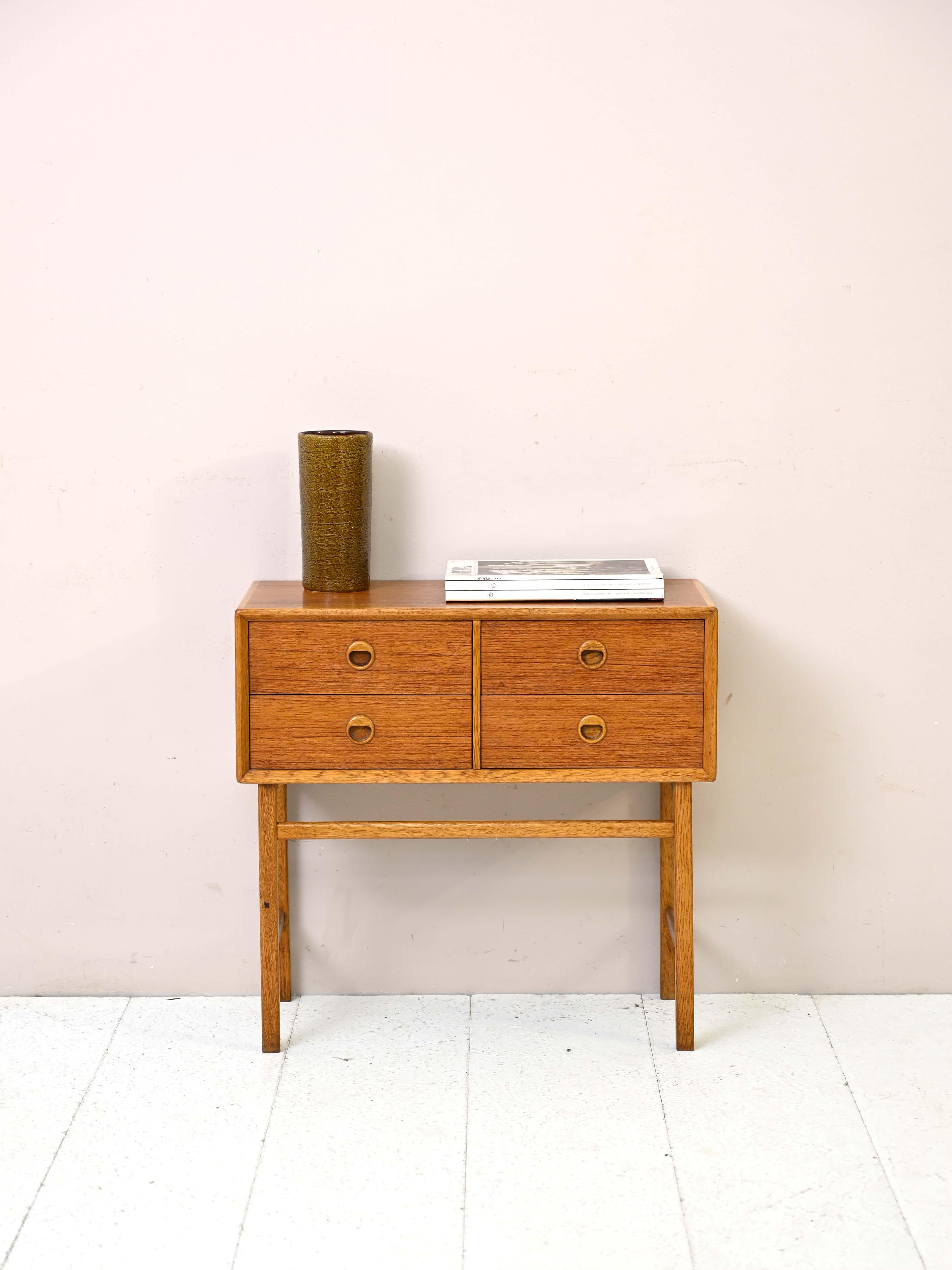 Small vintage Scandinavian chest of drawers.

An originally shaped piece of furniture consisting of a square-shaped frame with four drawers. 
The simple, straightforward design is enhanced by the use of the two woods of teak and oak and the handle