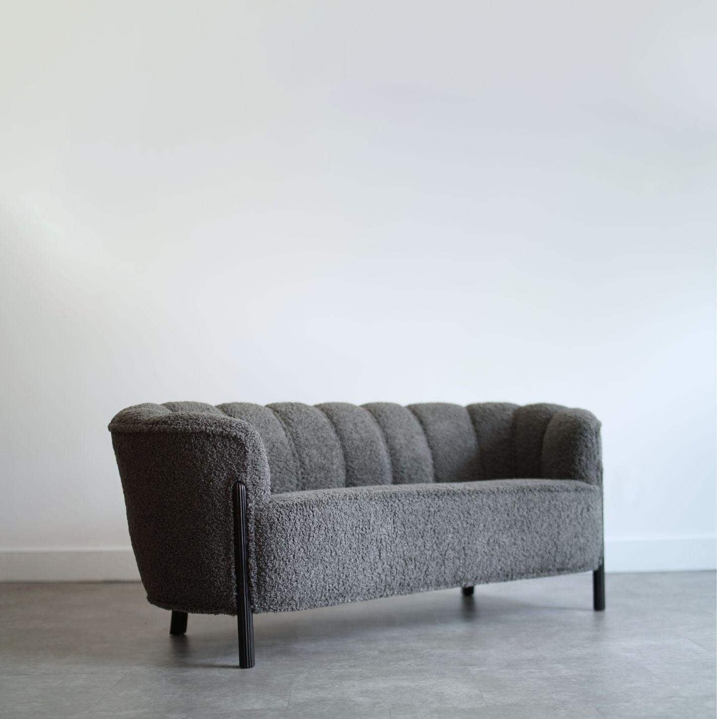 This original 1940s loveseat, crafted in the manner of Viggo Boesen, features a distinctive channelled back that enhances its elegant design. Completely restored, it is reupholstered in luxurious charcoal boucle fabric, offering both comfort and