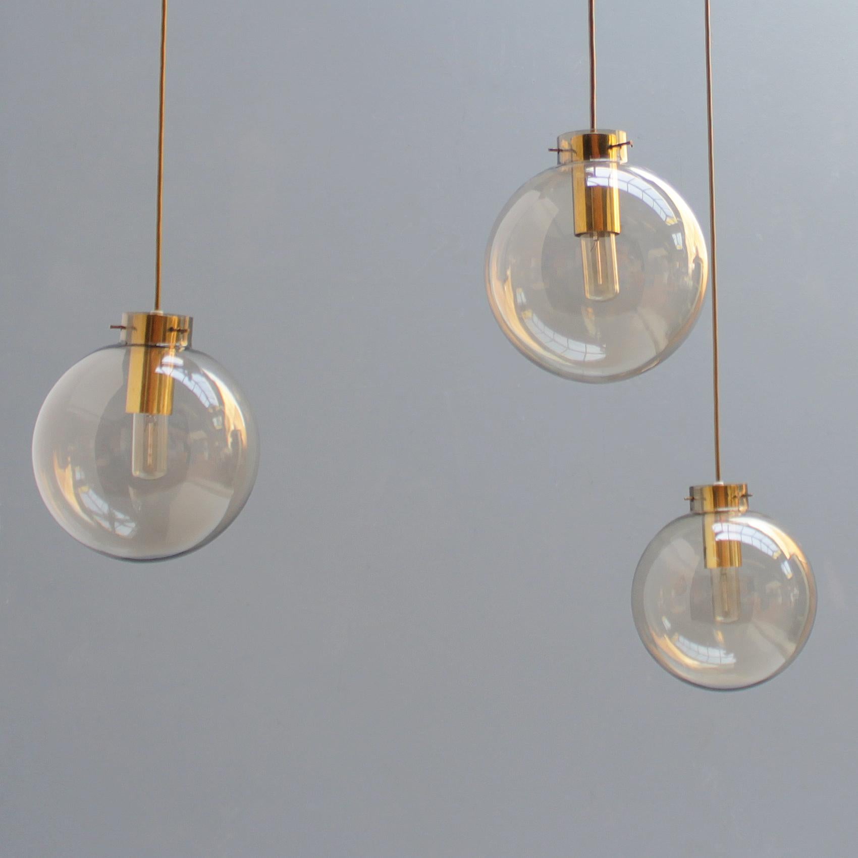 Fixture with three smoke glass spheres. Brass ceiling plate with three cable guides. You can make your own configuration by distributing the three guides across the ceiling. The length of the cable is also adjustable. Beautifully crafted details and