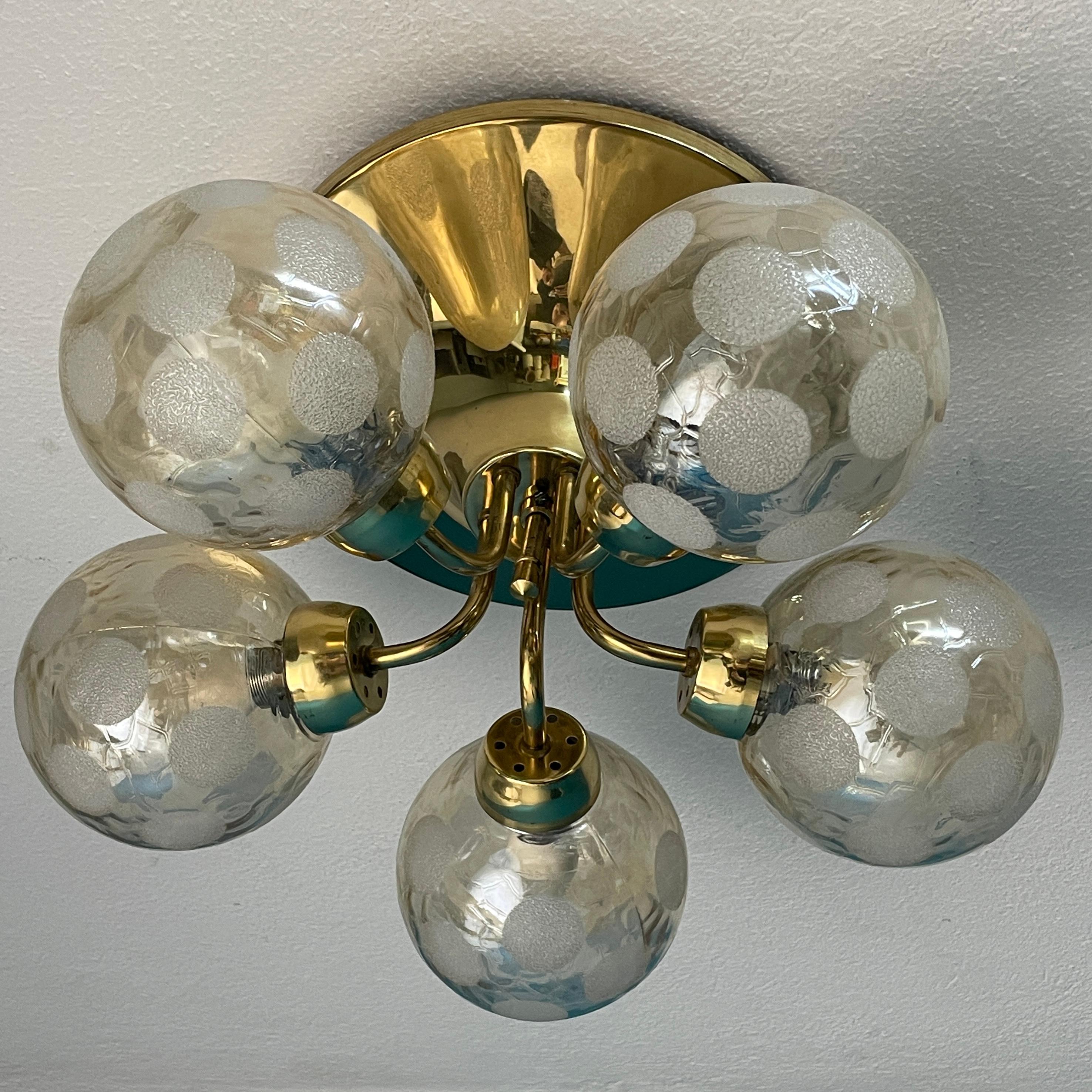 Beautiful Ceiling lamp, manufactured by Hyval, was designed in the 1970s. The brass-framed ceiling lamp consists of five branches, each covered with a surface-decorated glass sphere. The decorative but elegant ceiling lamp exudes the aesthetics of