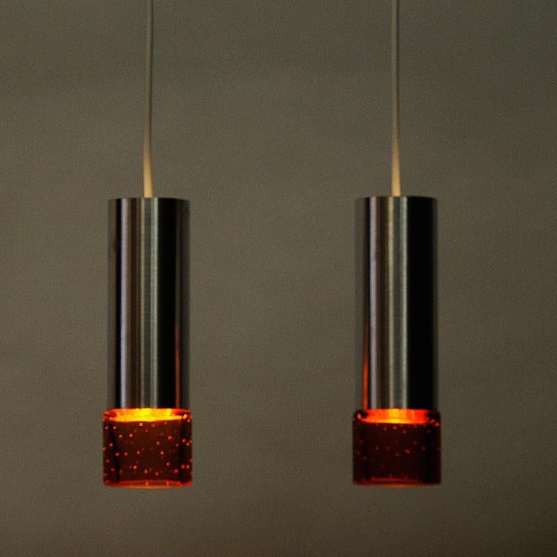 Lovely midcentury pair of pendants to be used both as ceiling -and windowlamps. The lamps has a metal cylinder base with beautiful goldish glass shade cup underneath. The circular glass shades have small closed airbubbles in the glass. Nice calm