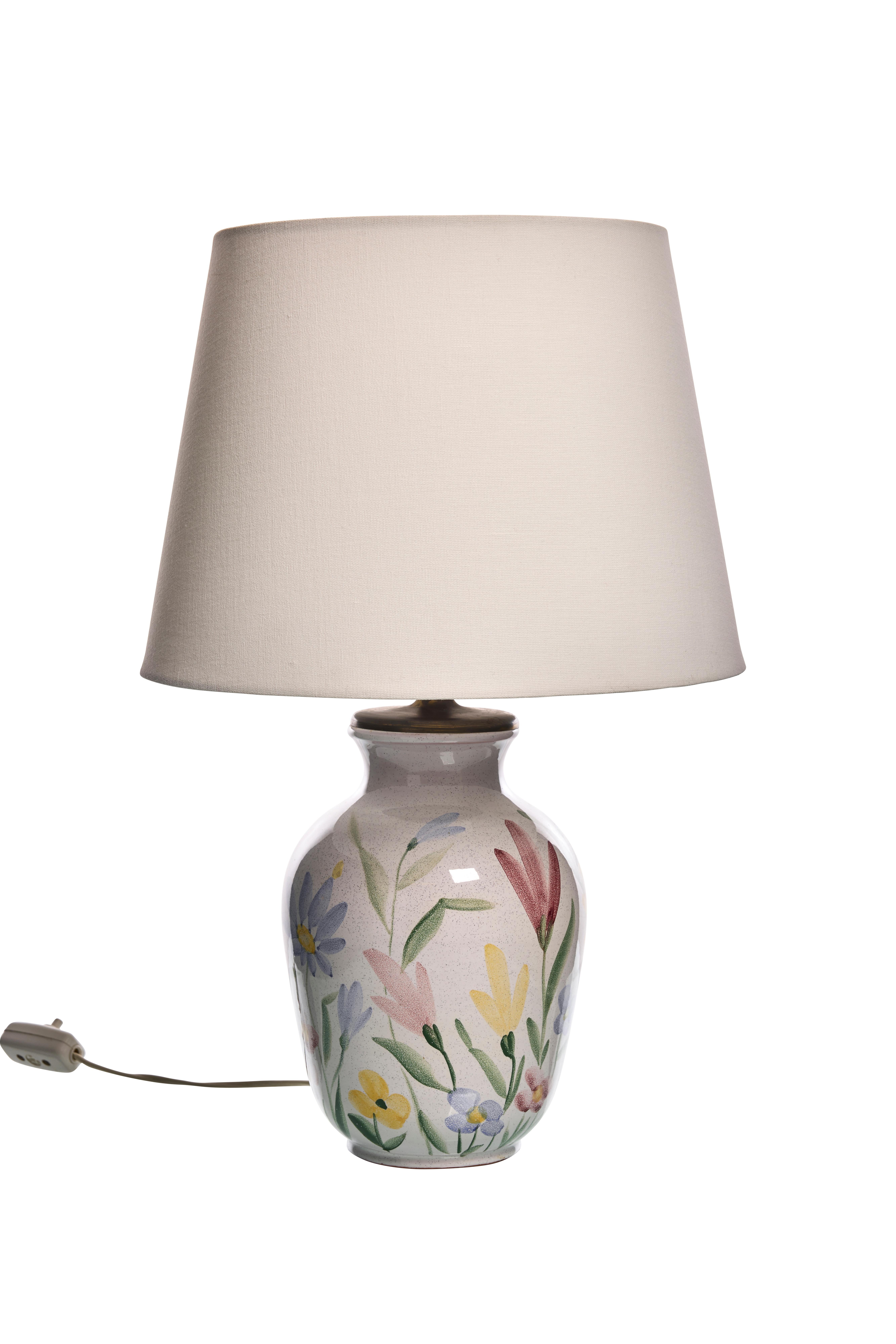 Beautiful ceramic lamp by Ulla Ahlgren with decoration of colorful flowers painted on the base of the lamp. 
This lamp is an elegant compliment to your home. The lamp is beautiful both off and on.