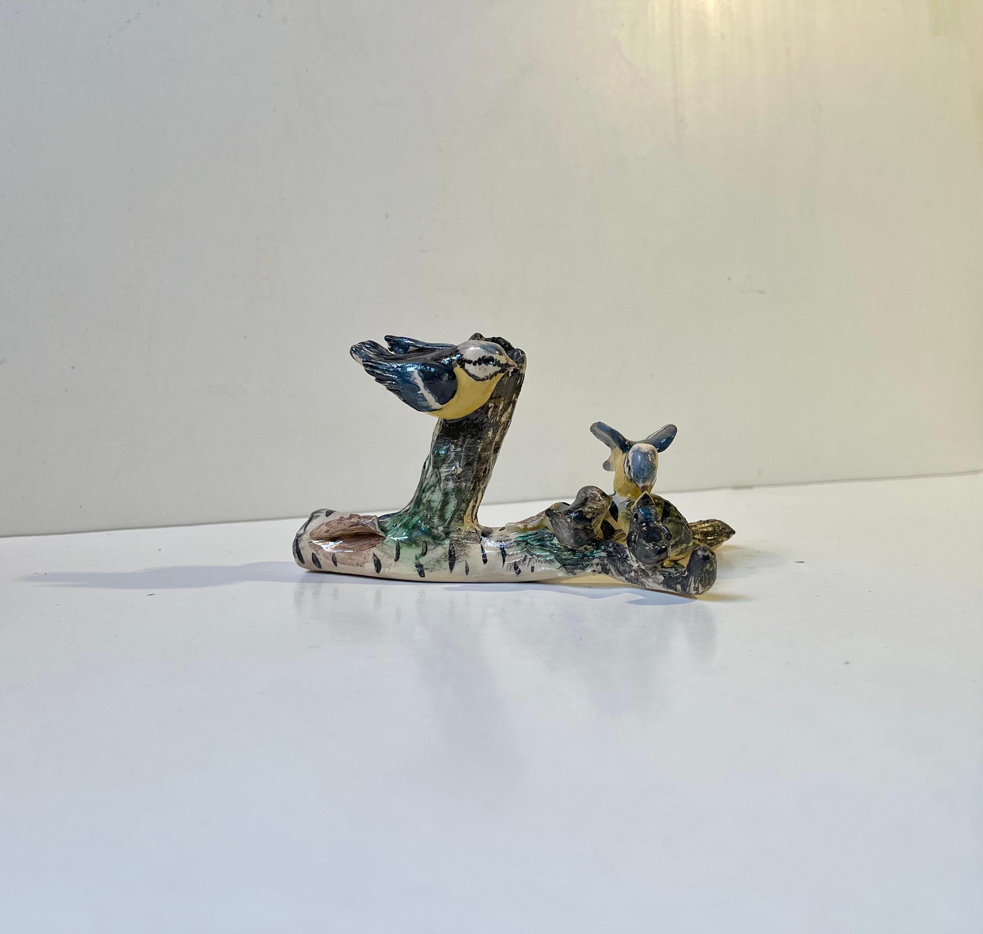 A naturalistic pen-holder in the shape of this glazed ceramic micro cosmos with a blue tit family (Parus caeruleus) going on with life on an old 'tired' birch wood branch with cracks and peeling. Signed: E. W. - unknown Danish ceramist. Obviously by