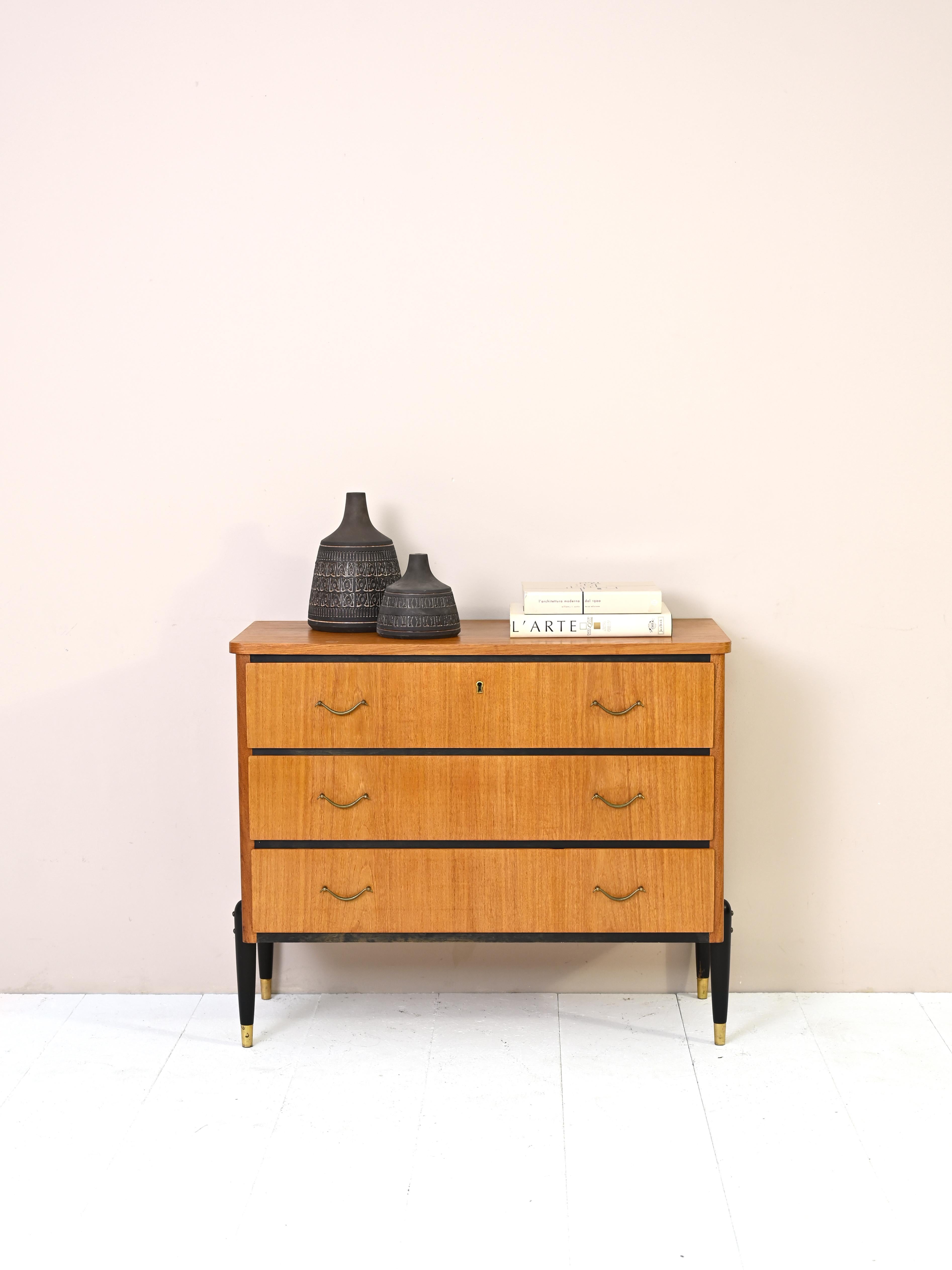 Teak cabinet with 3 drawers produced in the 1960s.
Consisting of a teak wood frame and enriched with metal elements, used for the
handles of the drawers and for the toe of the legs.
The details of the black-painted wood give uniqueness and