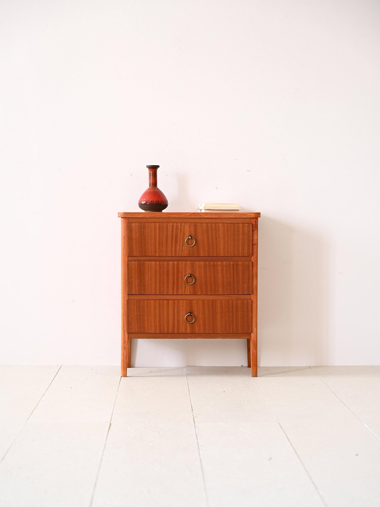 Vintage cabinet with three drawers.

This small chest of drawers is ideal as a piece of furniture for the entryway, bathroom or as a bedside table for the bedroom. 
Featuring a mahogany frame that thanks to the wood grain and the golden handle of