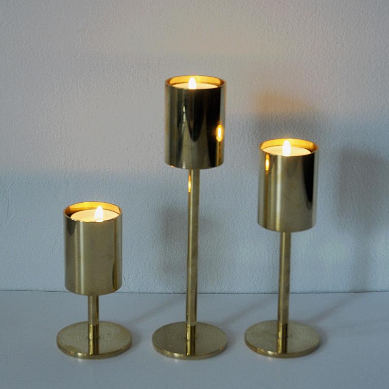Three stylish brass candlelight holders for tea lights. Cylinder-shaped top on a brass pole and base. Mix them as you prefer, as a collection of three or in a row of three. Lovely either way. All have the same diameter but are in different heights