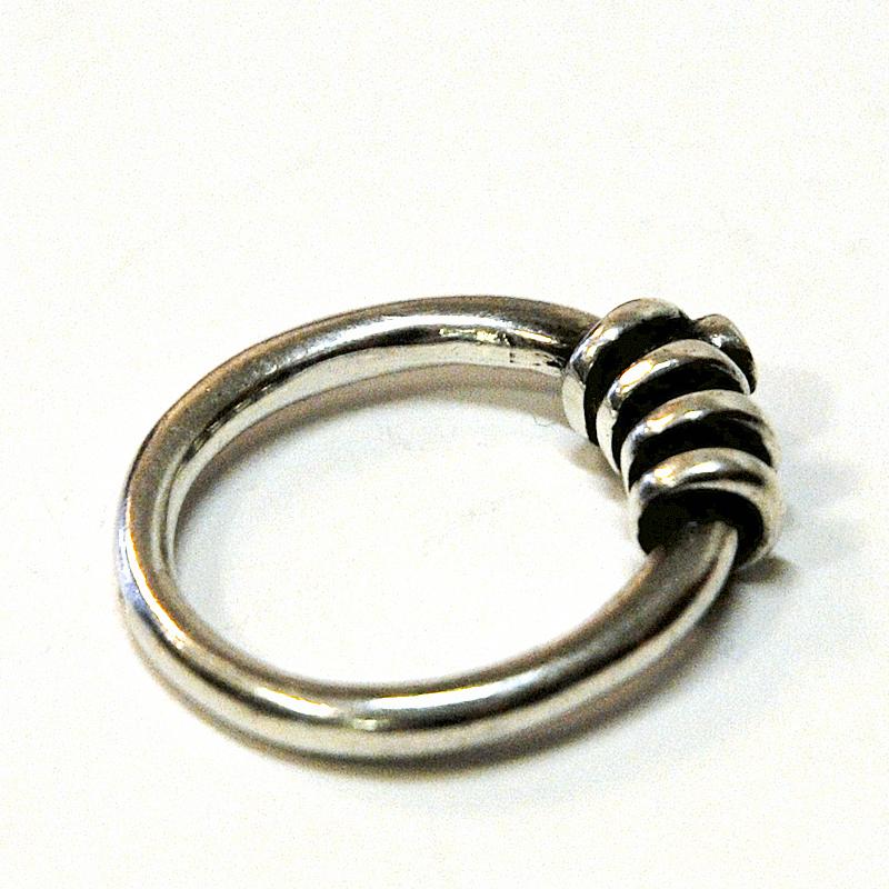 Decorative vintage Scandinavian silvering with a small rock crystal stone on top and silver curls around the band.

Silver stamped: 925. Measures: Inner diameter is 16mm, total height of ring 25 mm. Scandinavian design. Nice and natural patina and
