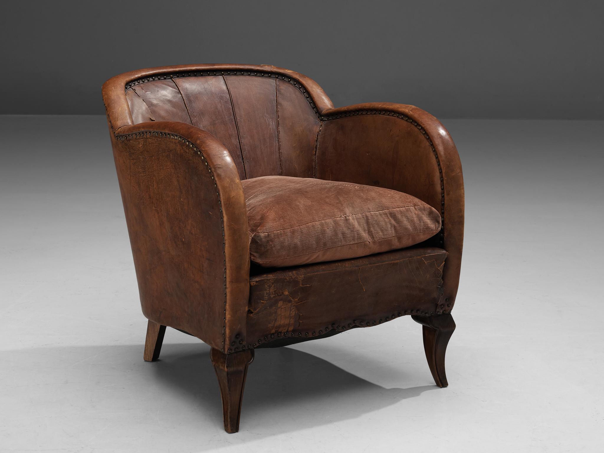 Lounge chair, leather, wood, Scandinavia, 1940s. 

Grand Scandinavian club chair in patinated cognac leather made by an unknown cabinetmaker. The wooden front legs are carved in an elegant cabriole design that suits perfectly with the rounded