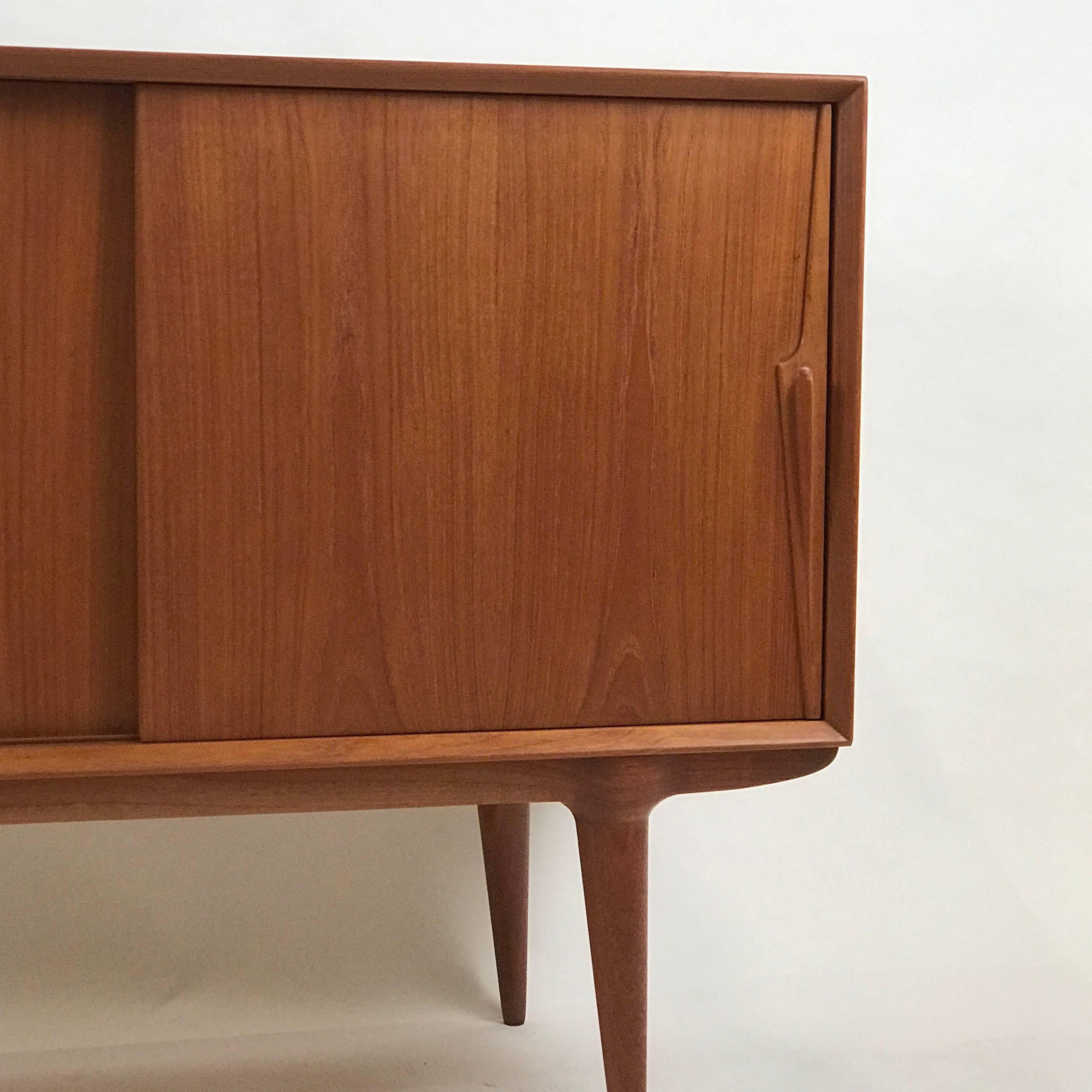 A freshly refinished teak sliding door credenza with four drawers.