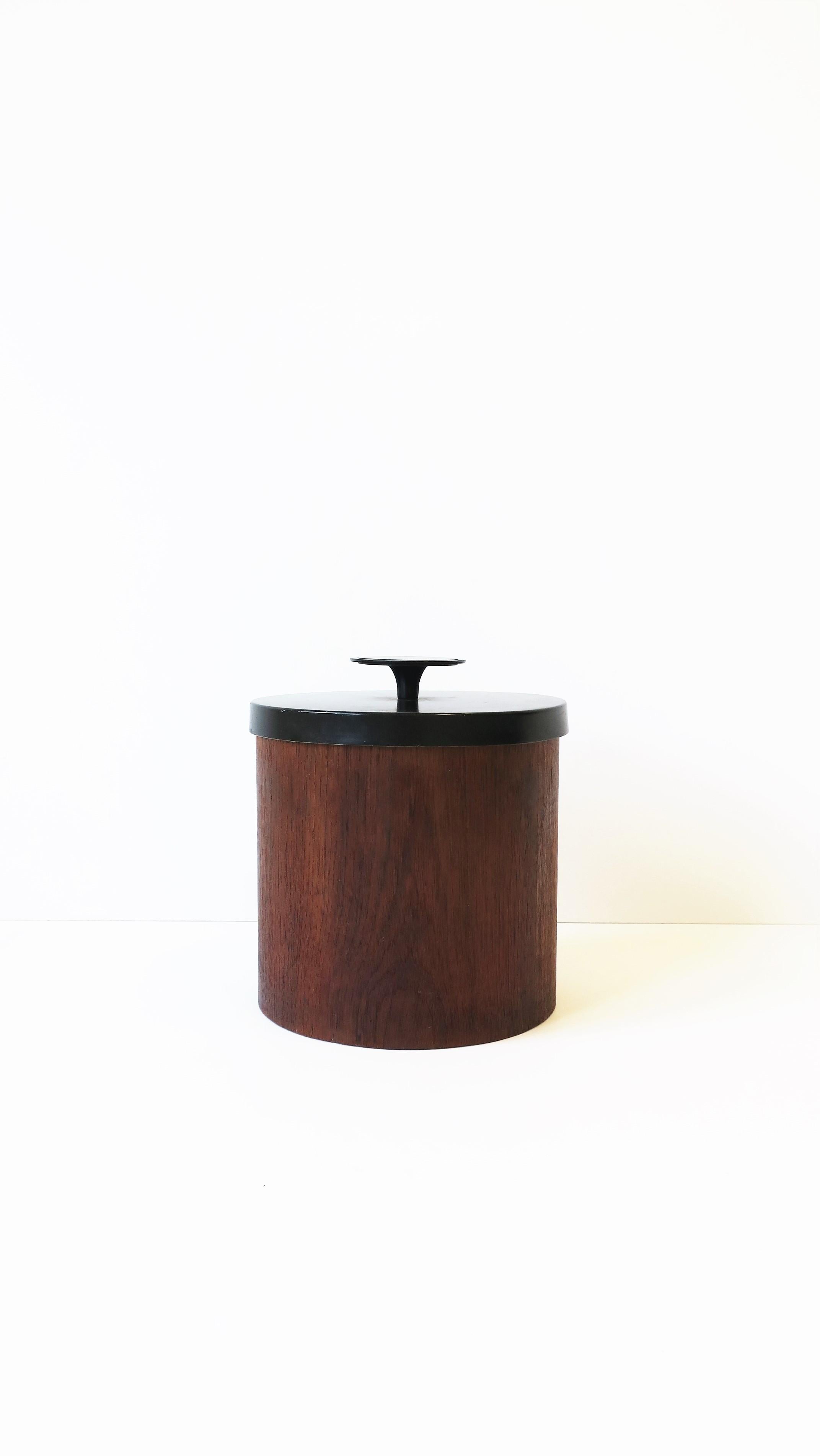 A great Scandinavian Modern ice bucket, circa mid-20th century, Denmark. Ice bucket has a brown teak wood exterior, red plastic interior and a black metal lid with knob. A great piece for any bar, bar cart, entertaining area, etc. Marked 