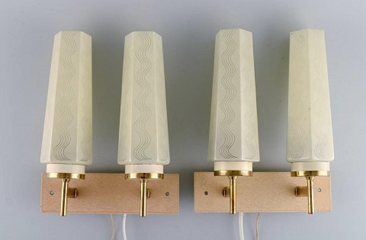 Scandinavian designer, a pair of double brass wall lamps with glass shades. Mid-20th century.
Measures: 23.5 x 19 cm.
In excellent condition with signs of use.